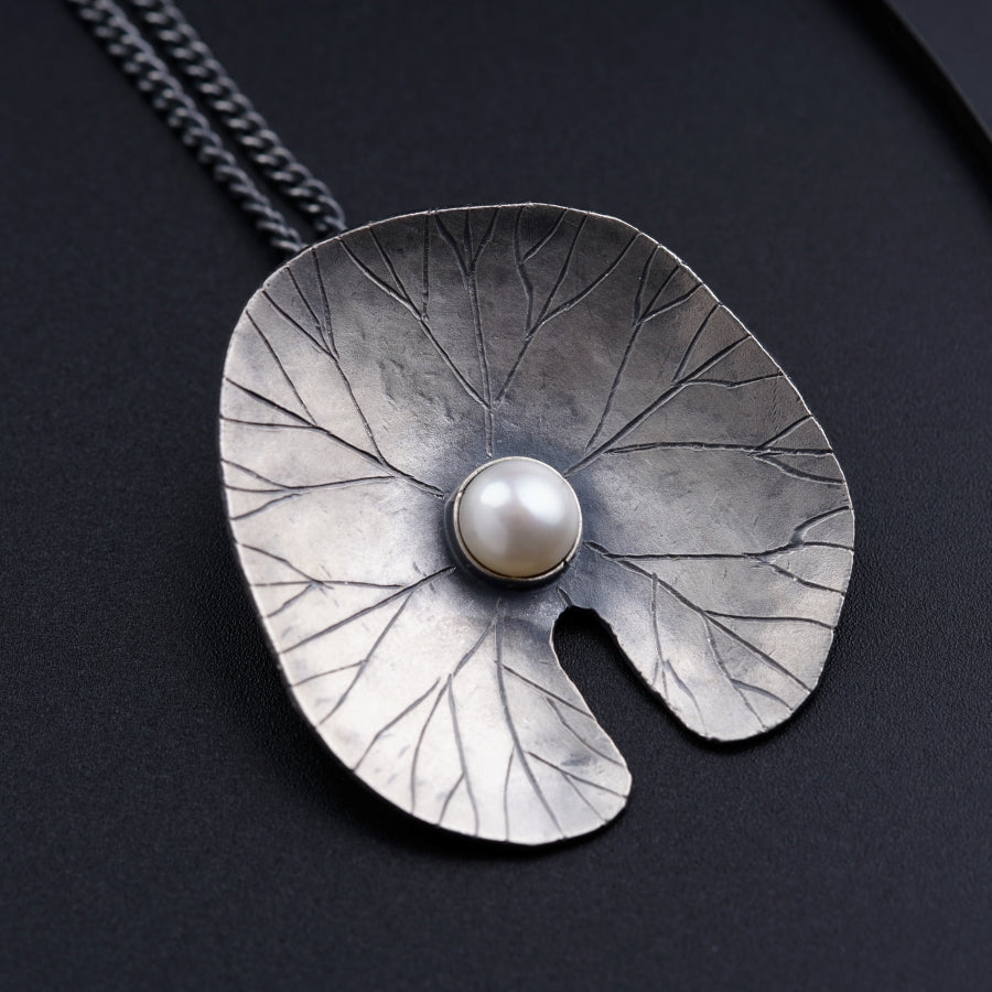 a silver necklace with a pearl in the center