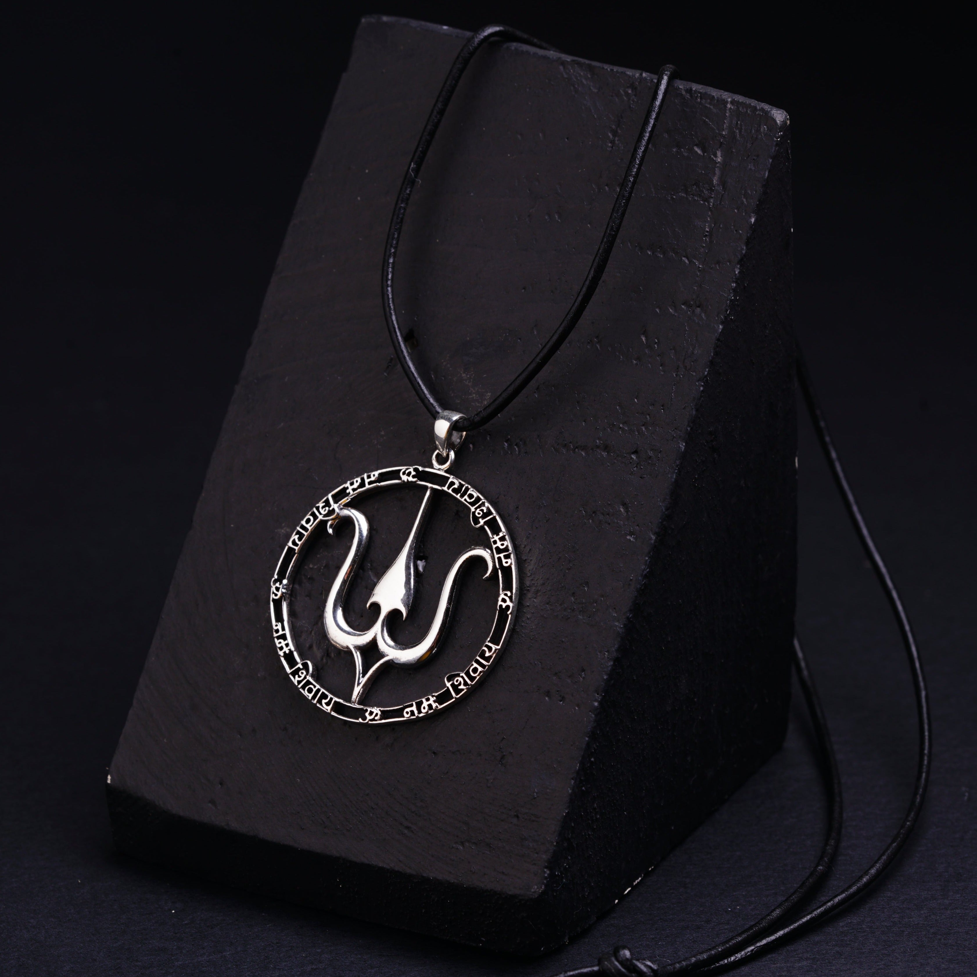 a black necklace with a silver pendant on a black box