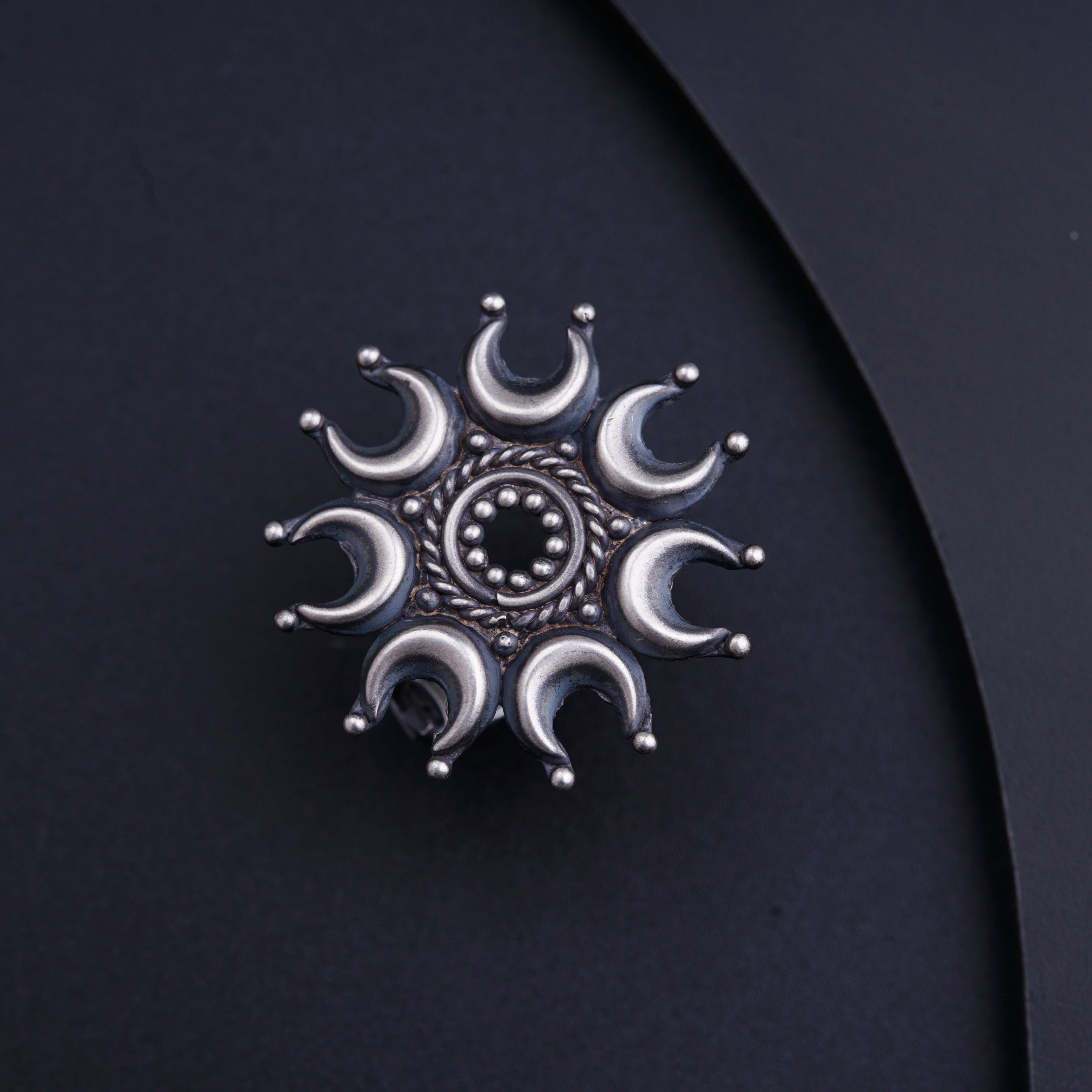 a silver brooch sitting on top of a black surface