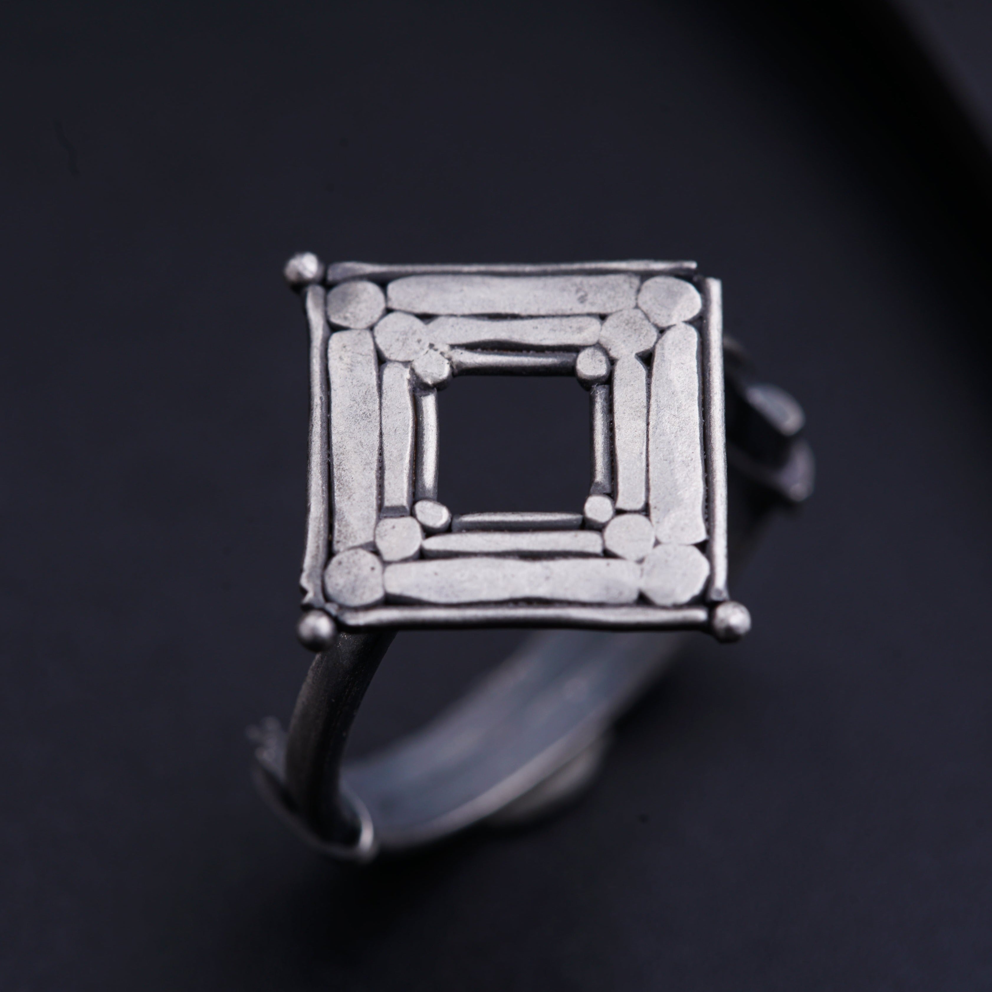 a silver ring with a square design on it