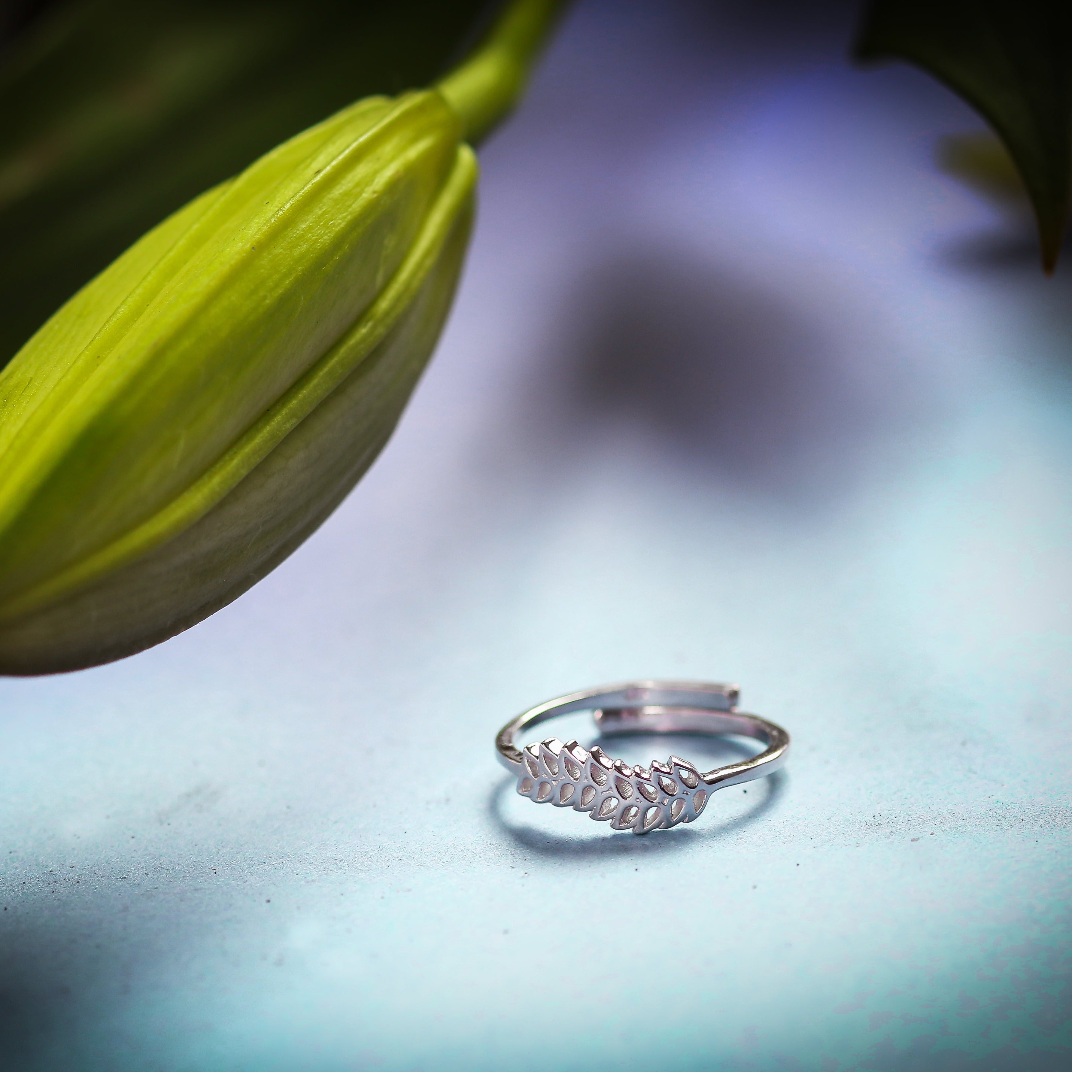 a silver ring sitting on top of a table next to a flower