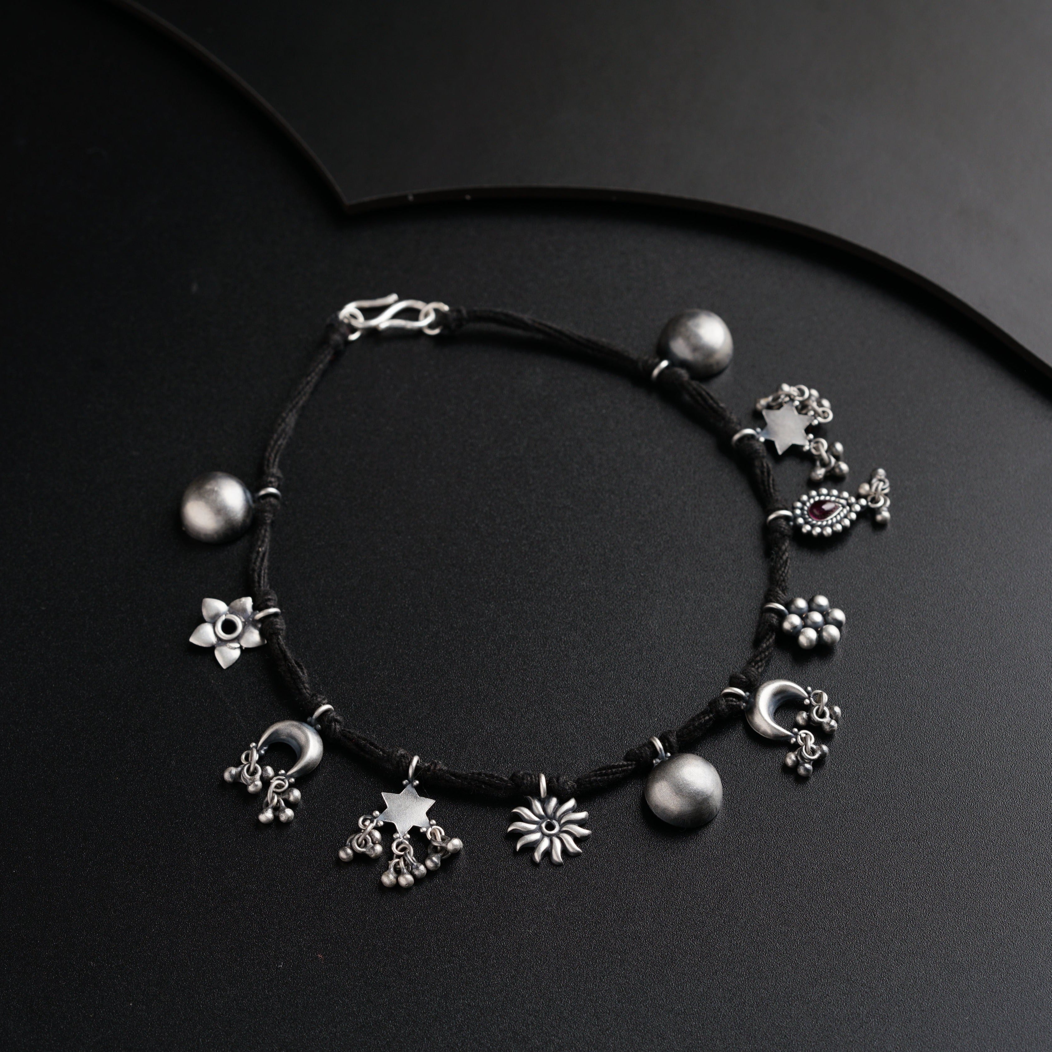a black string bracelet with silver beads and flowers
