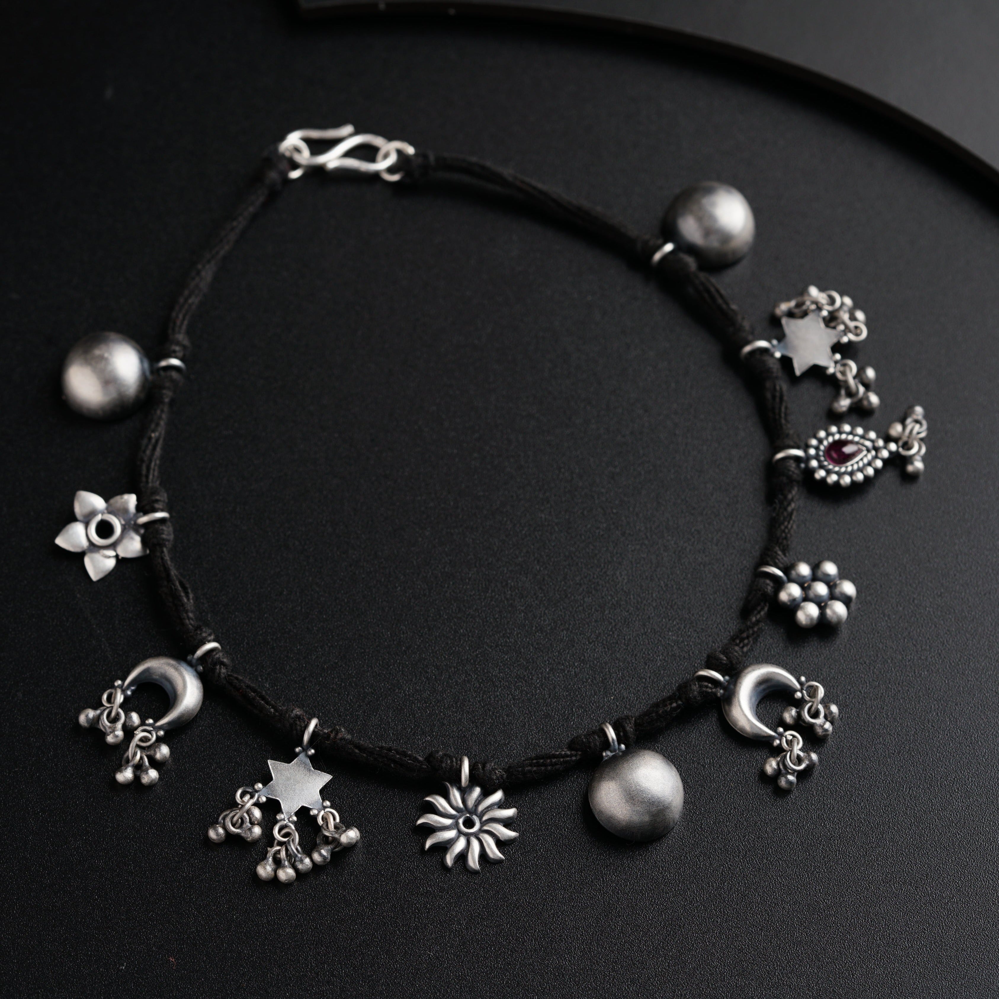 a black string bracelet with silver beads and charms