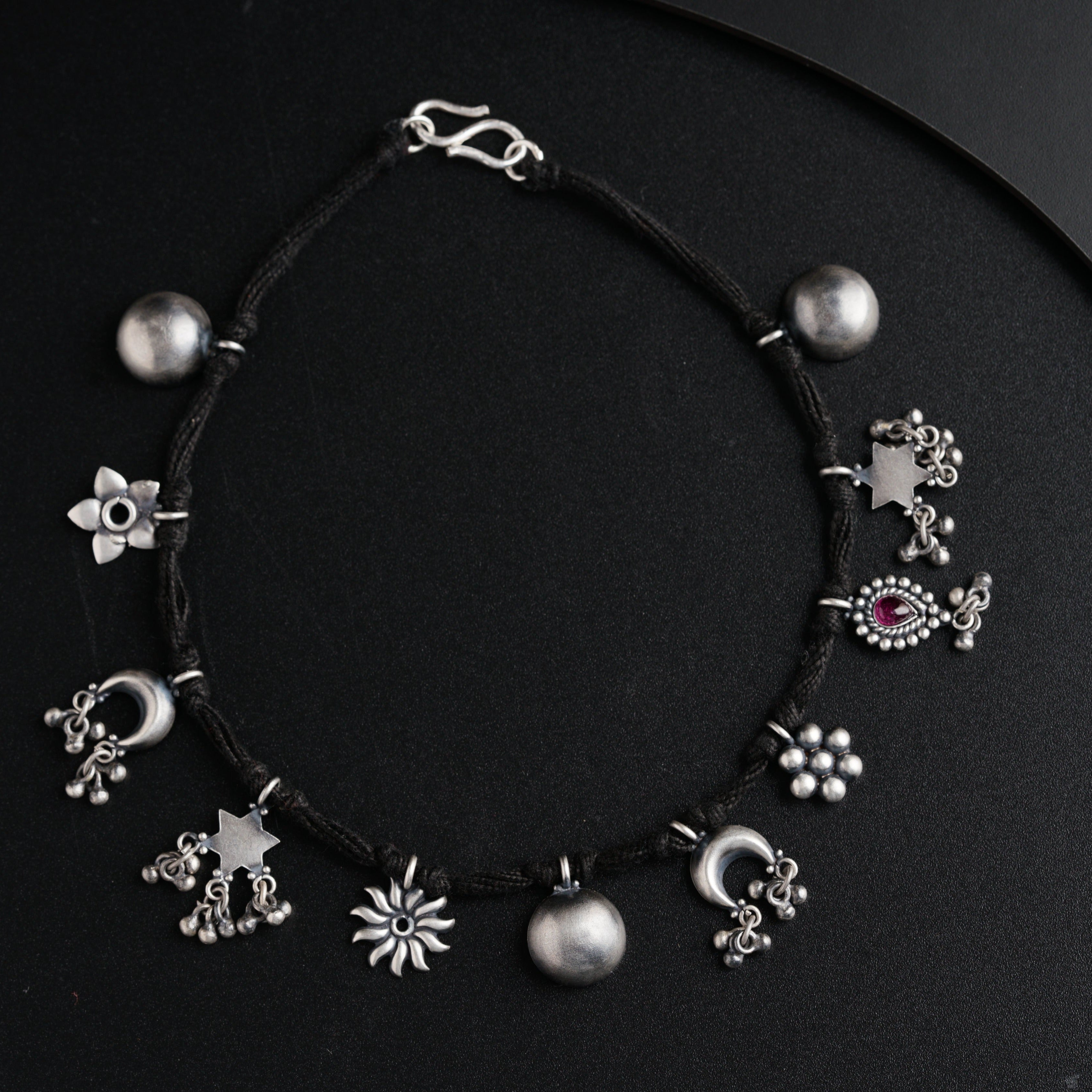 a black string bracelet with silver beads and charms