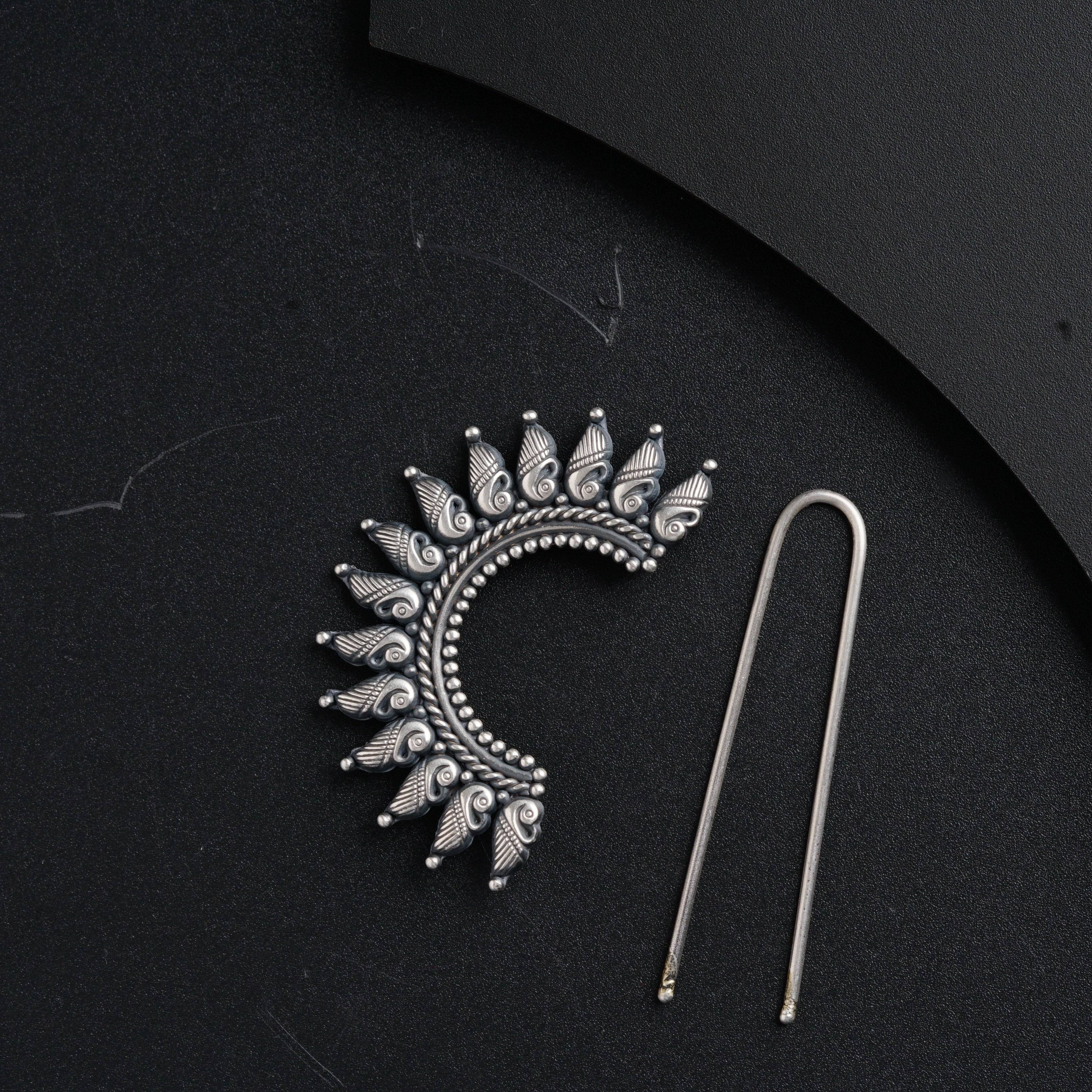 a pair of scissors and a brooch on a black surface