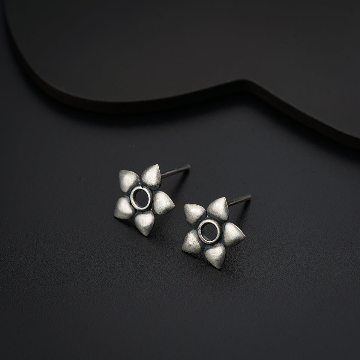 a pair of silver earrings sitting on top of a black surface