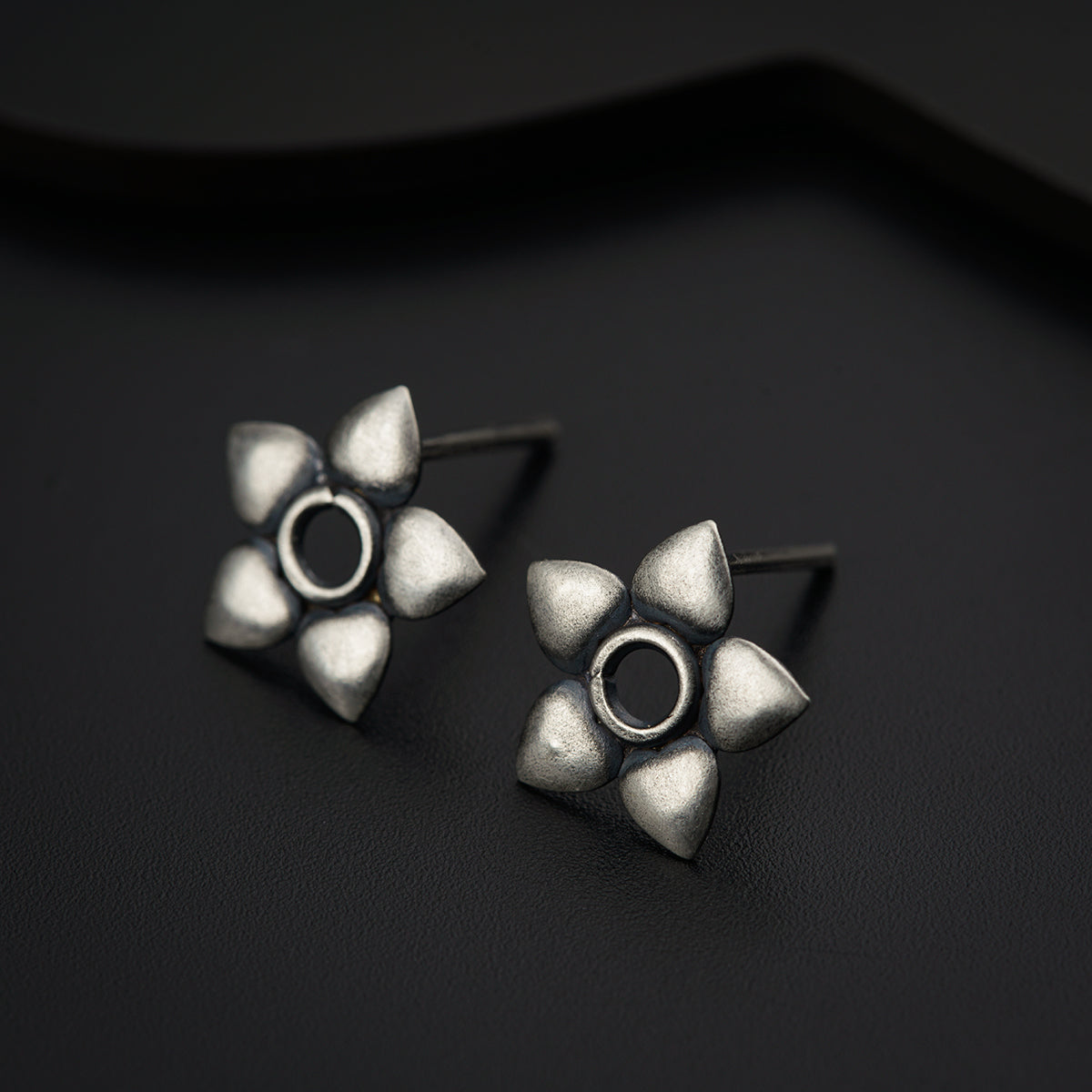 a pair of silver earrings sitting on top of a black surface