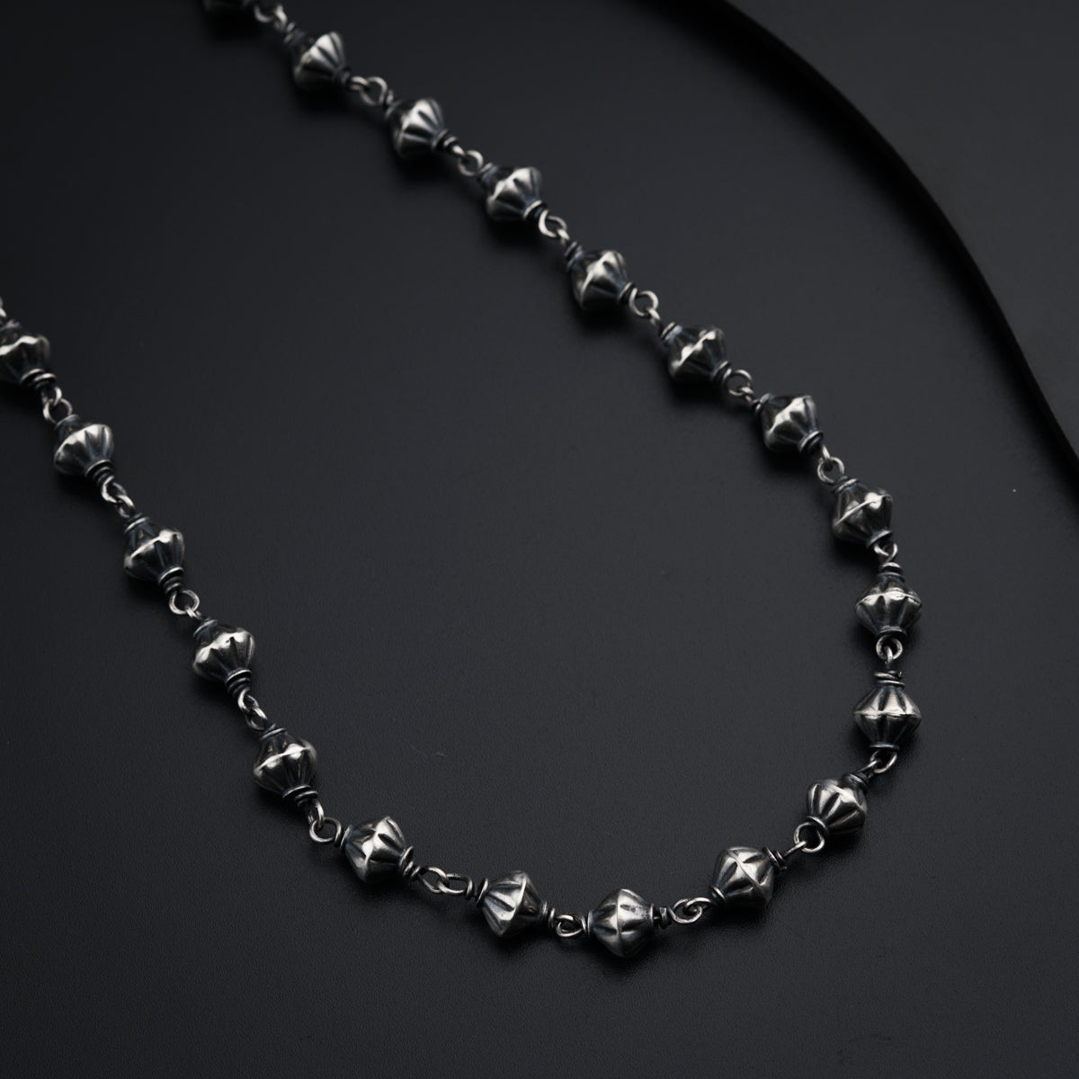 a black and silver necklace on a black surface