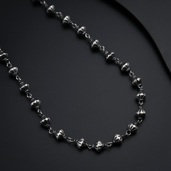 a black and silver necklace on a black surface