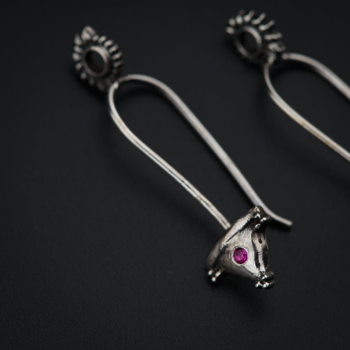 a pair of silver earrings with a pink stone