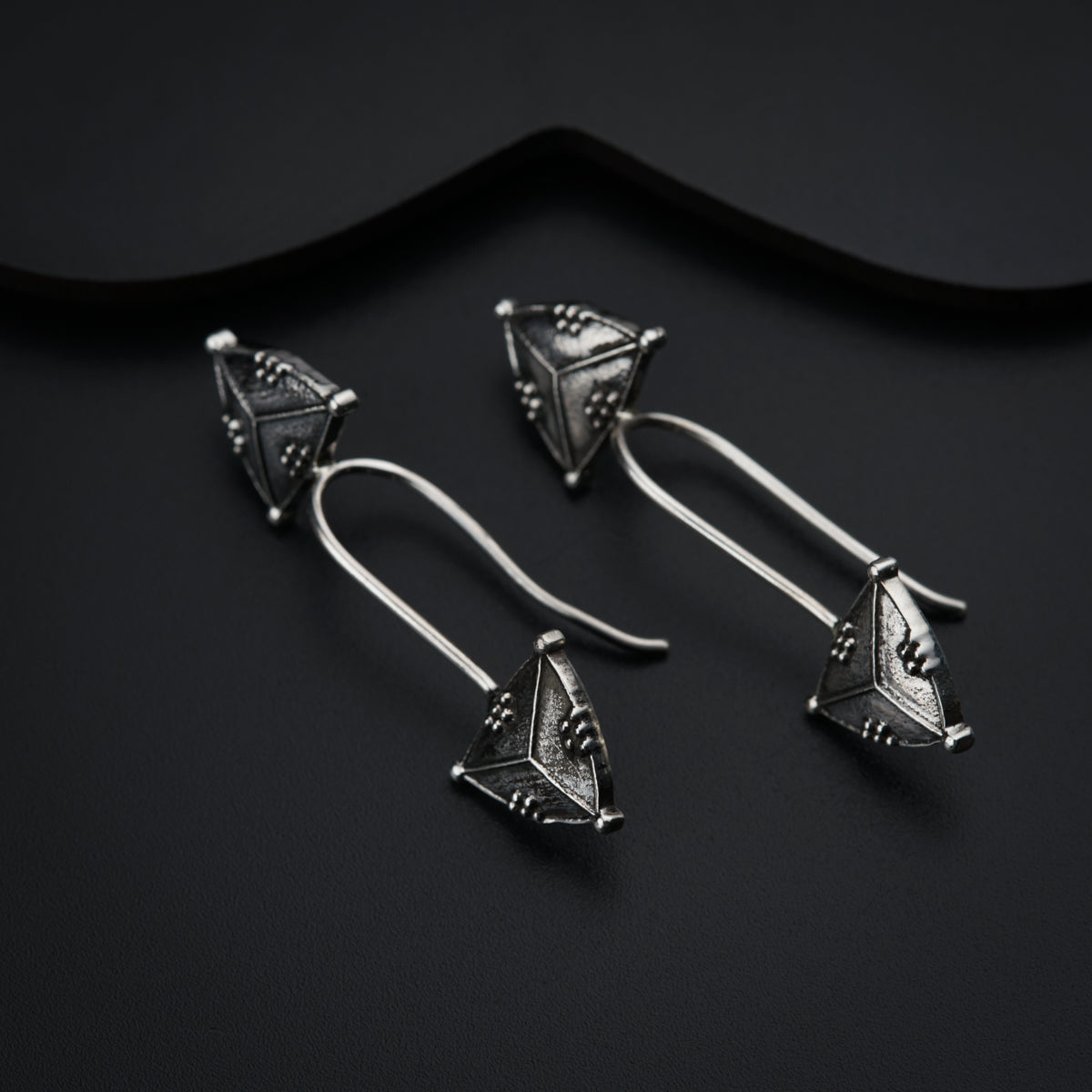 a pair of silver earrings on a black surface