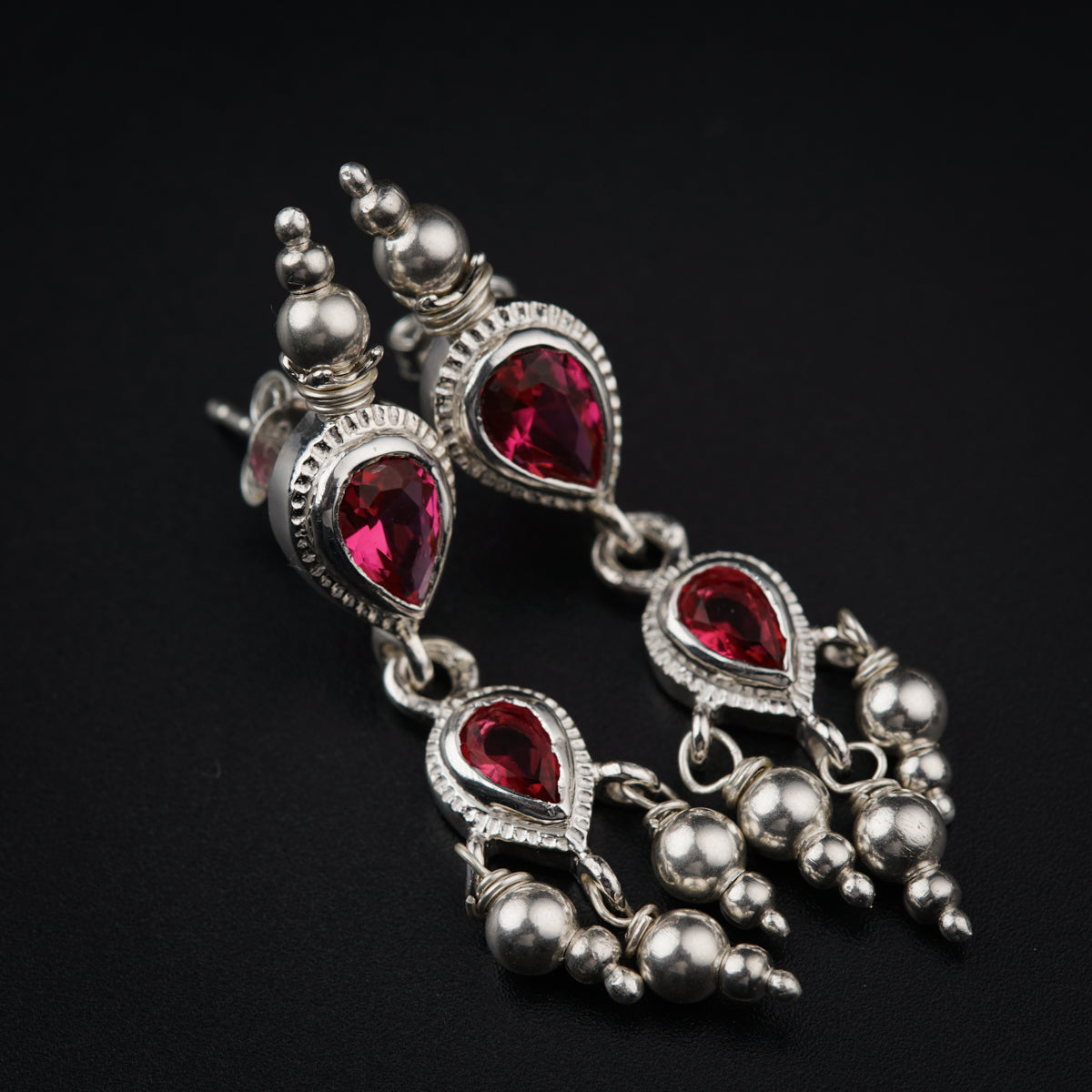a pair of red and silver earrings on a black background