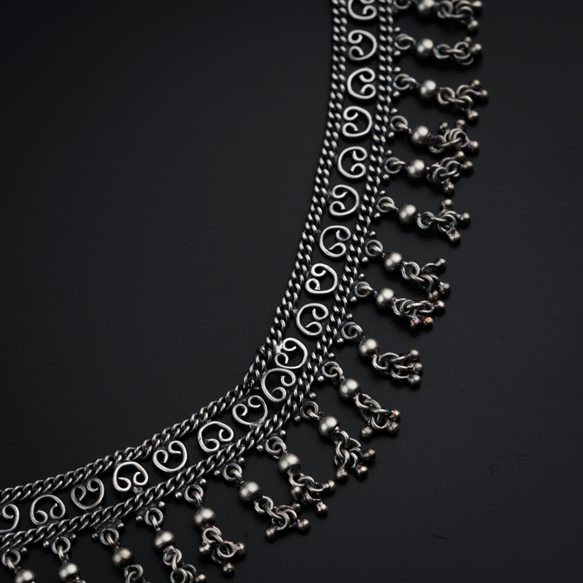 a silver necklace with metal balls and chains