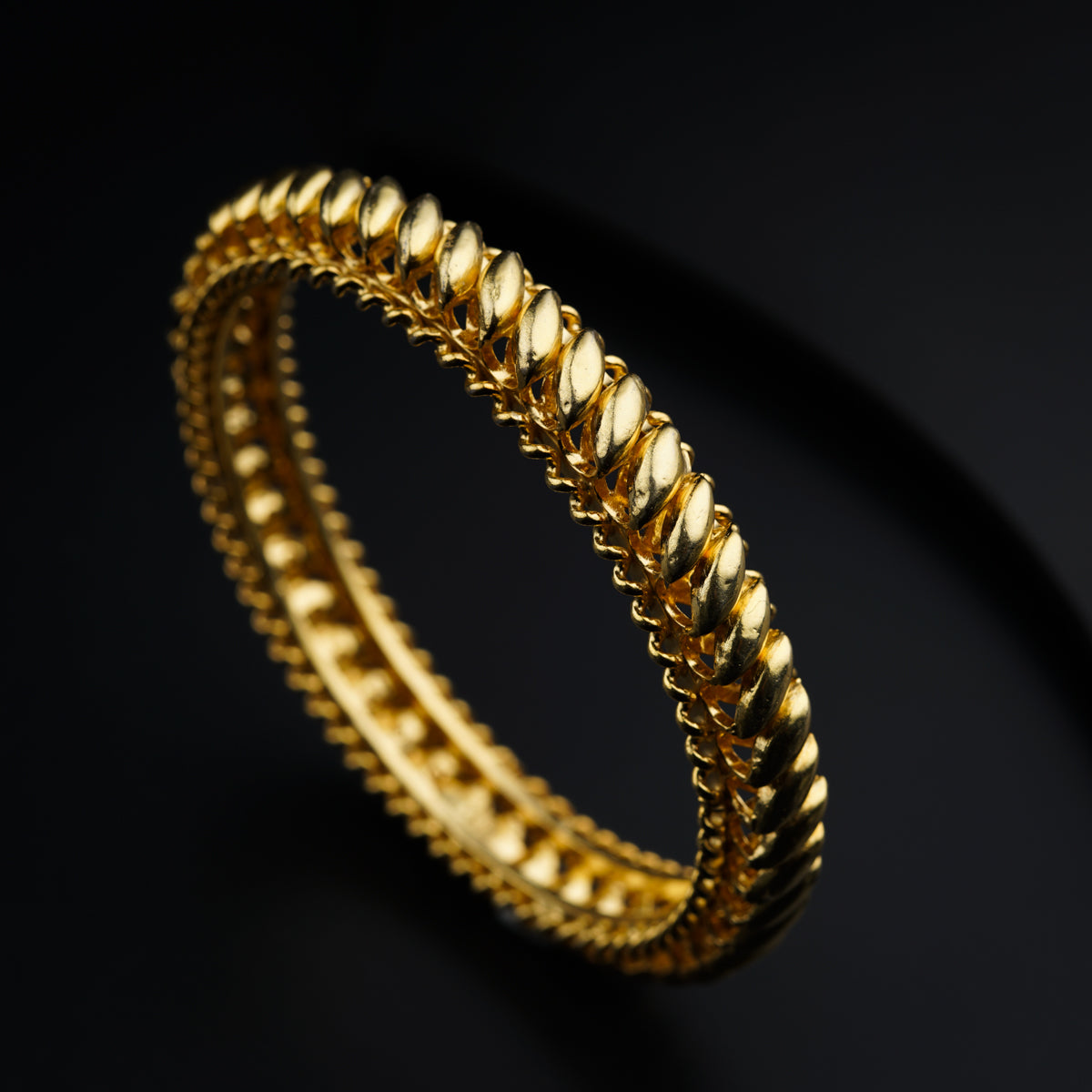 a close up of a gold bracelet on a black background