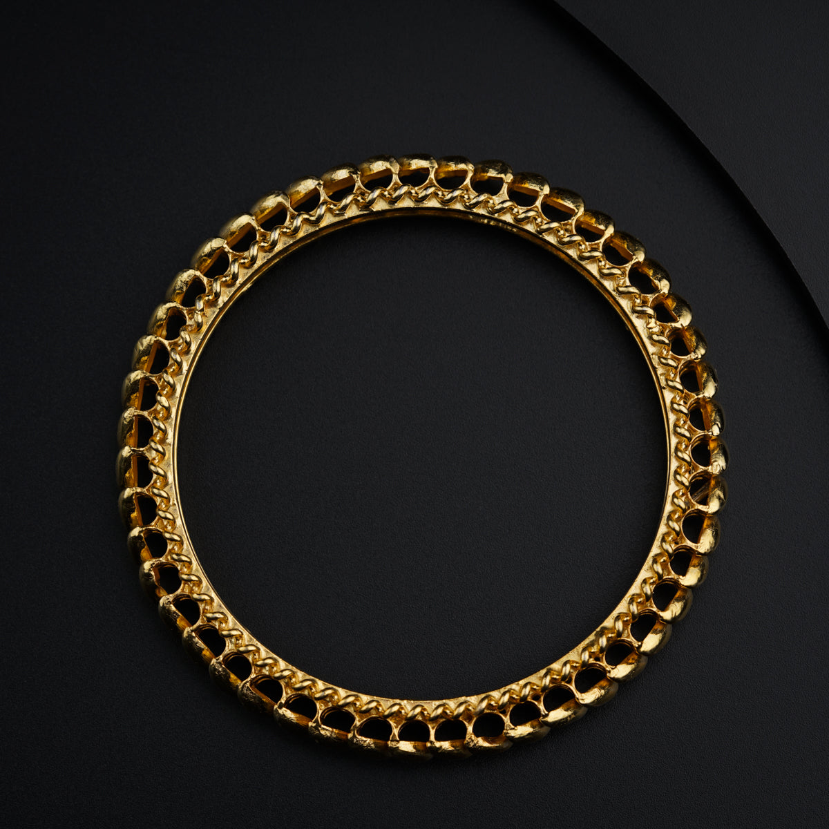 a gold chain bracelet on a black surface