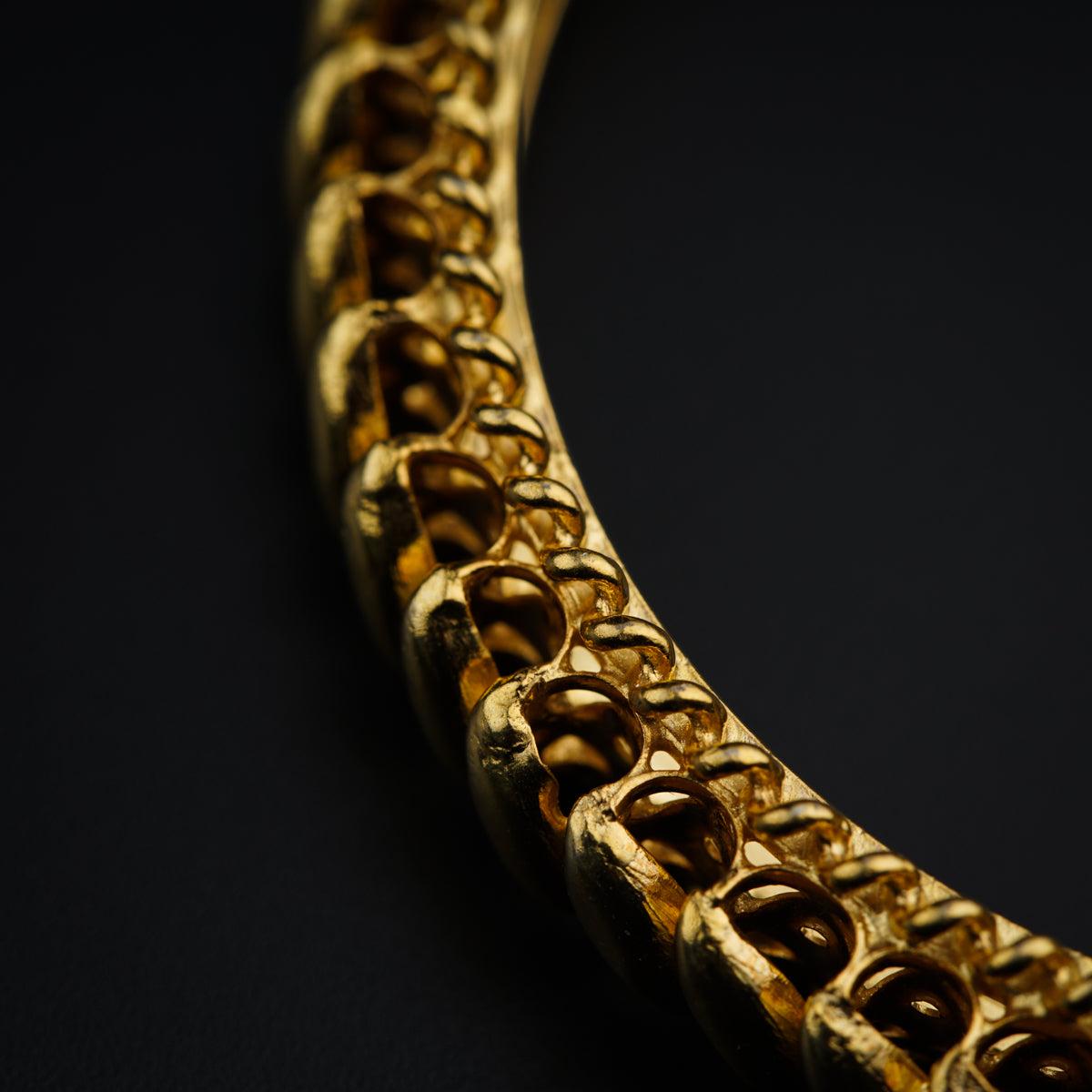 a close up of a gold necklace on a black surface
