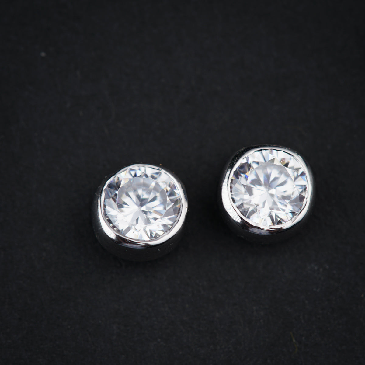 a pair of diamond studs on a black surface