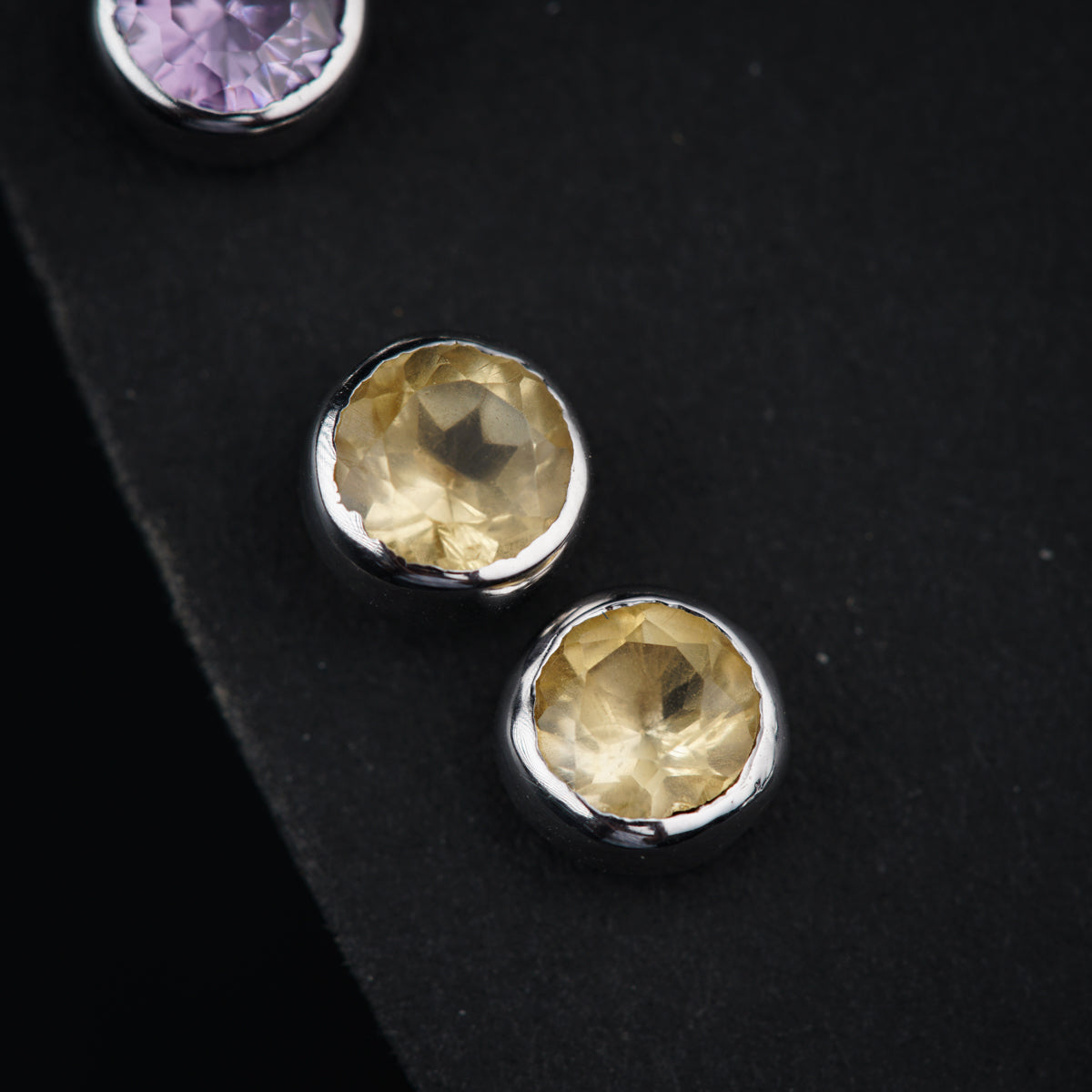 a pair of earrings with a yellow topaz and a purple topaz