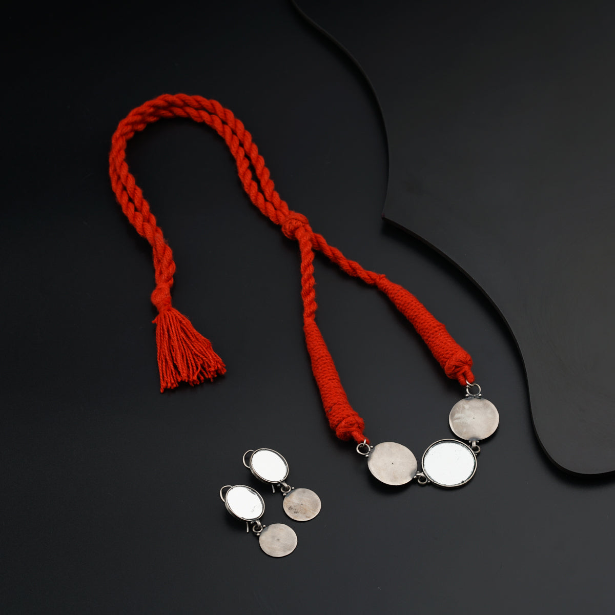a pair of earrings and a red rope on a black surface