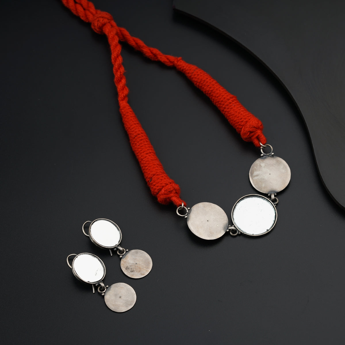 a pair of silver and red necklaces on a black surface