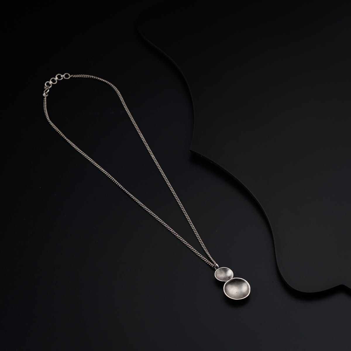 a silver necklace with two circles hanging from it