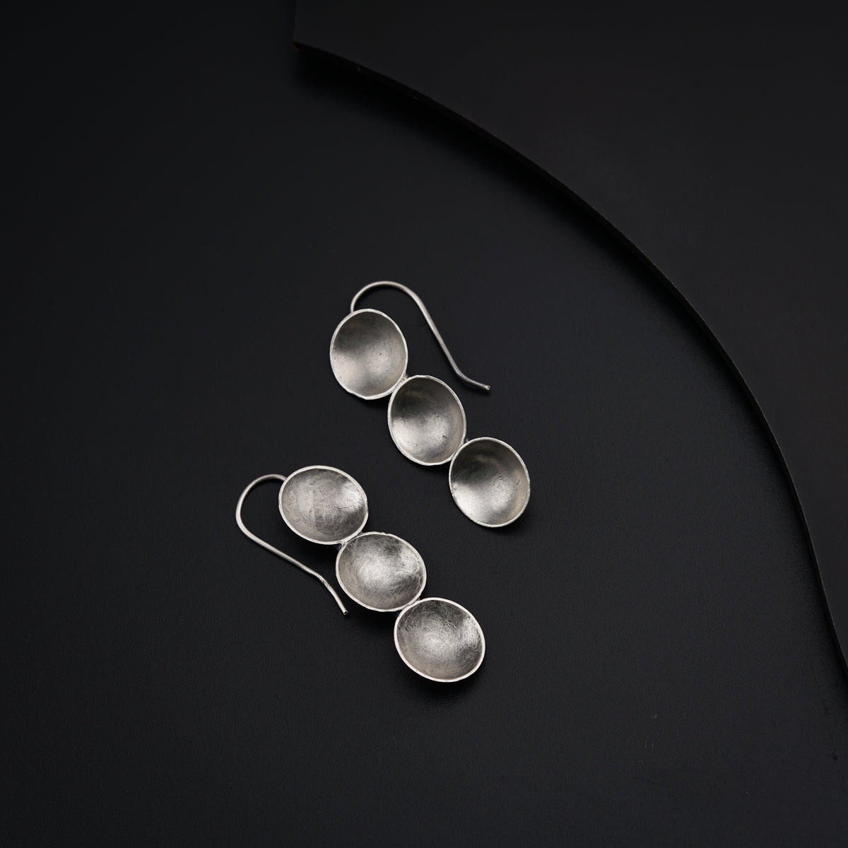 a pair of silver spoons sitting on top of a black surface
