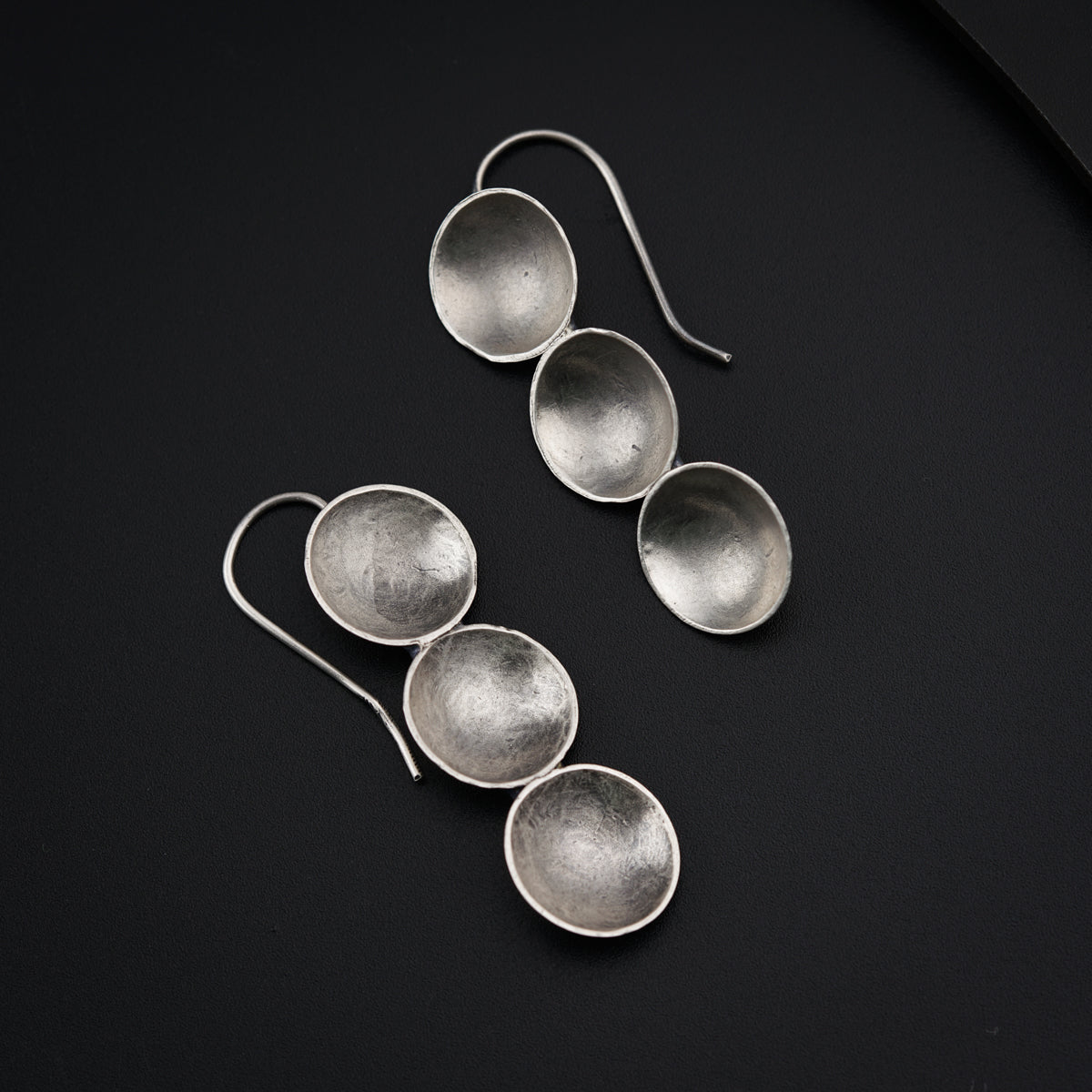 a pair of silver earrings sitting on top of a table