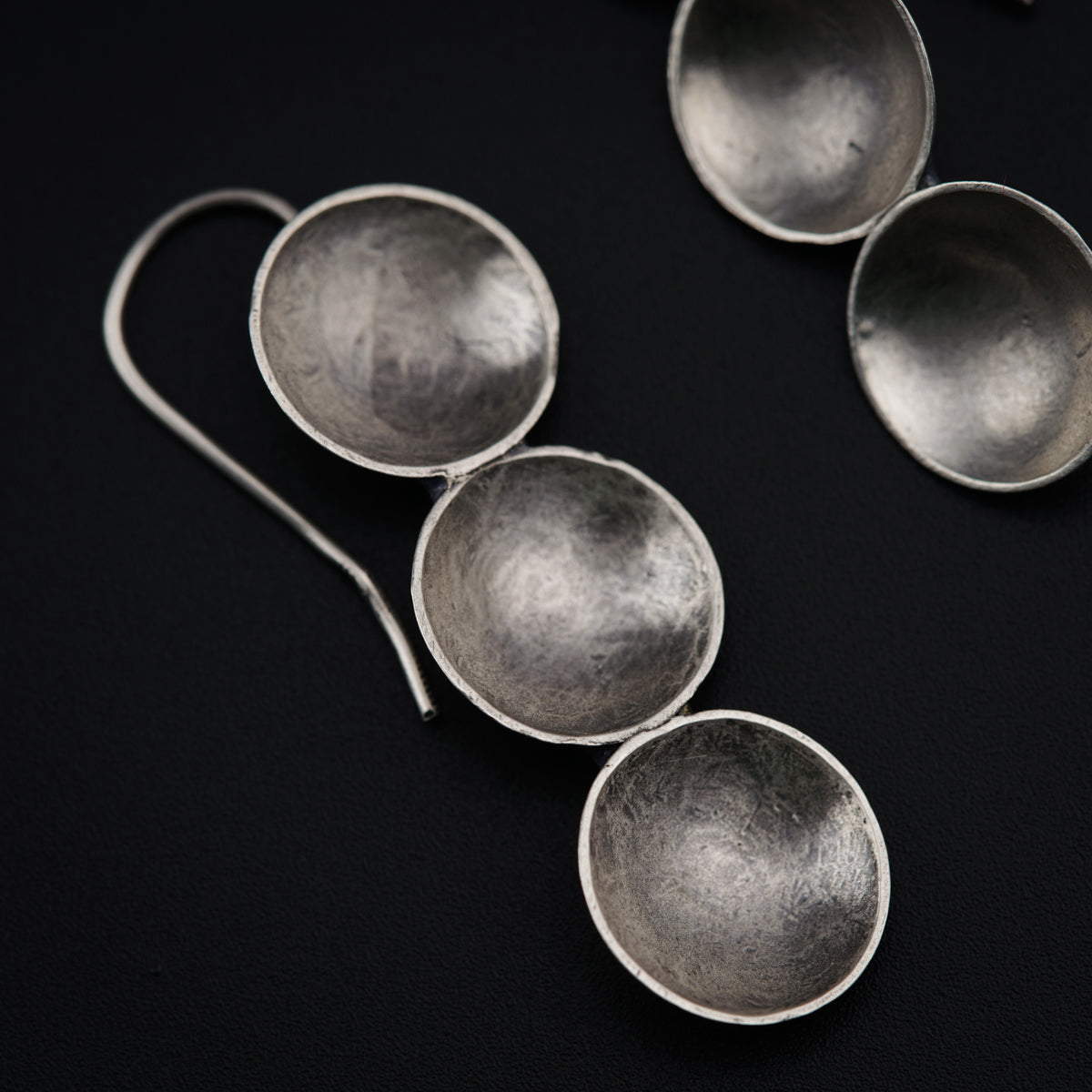 four silver spoons sitting on top of a black surface