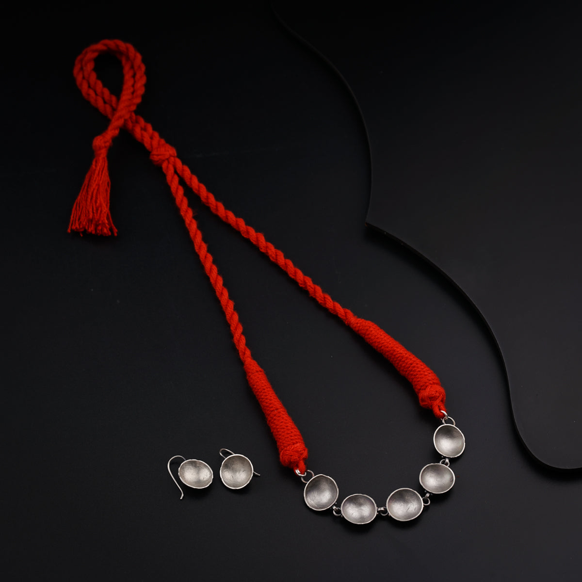 a red string with two silver balls and a tassel