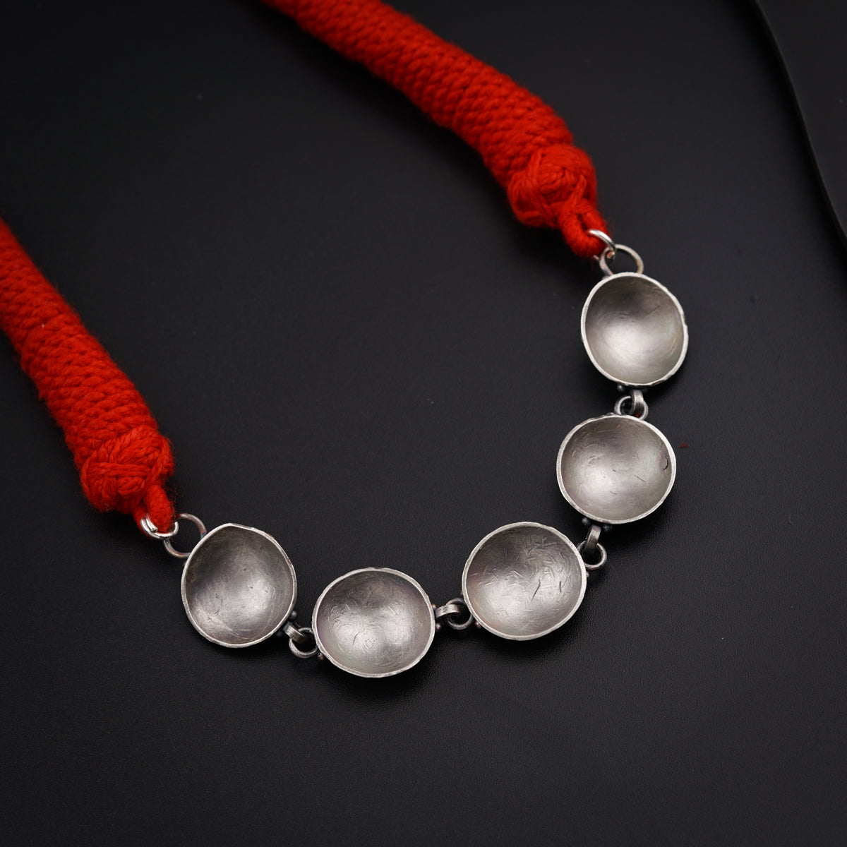 a silver necklace with three circles on a red cord