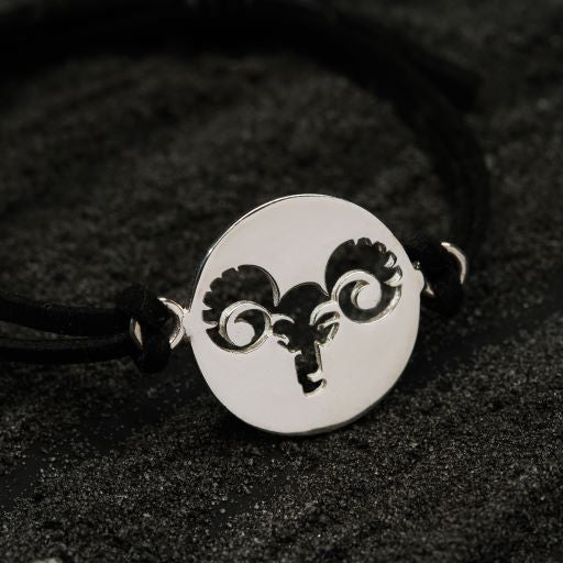 a black and white picture of a ram head on a leather bracelet