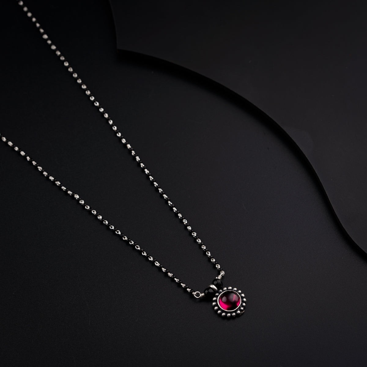 two necklaces on a black surface one with a pendant and the other with a