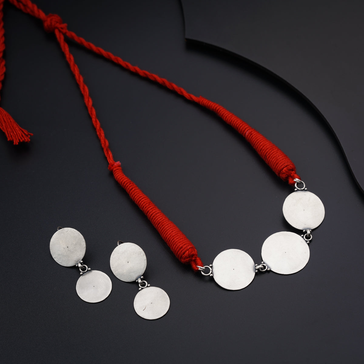 a necklace with three discs and a red tassel