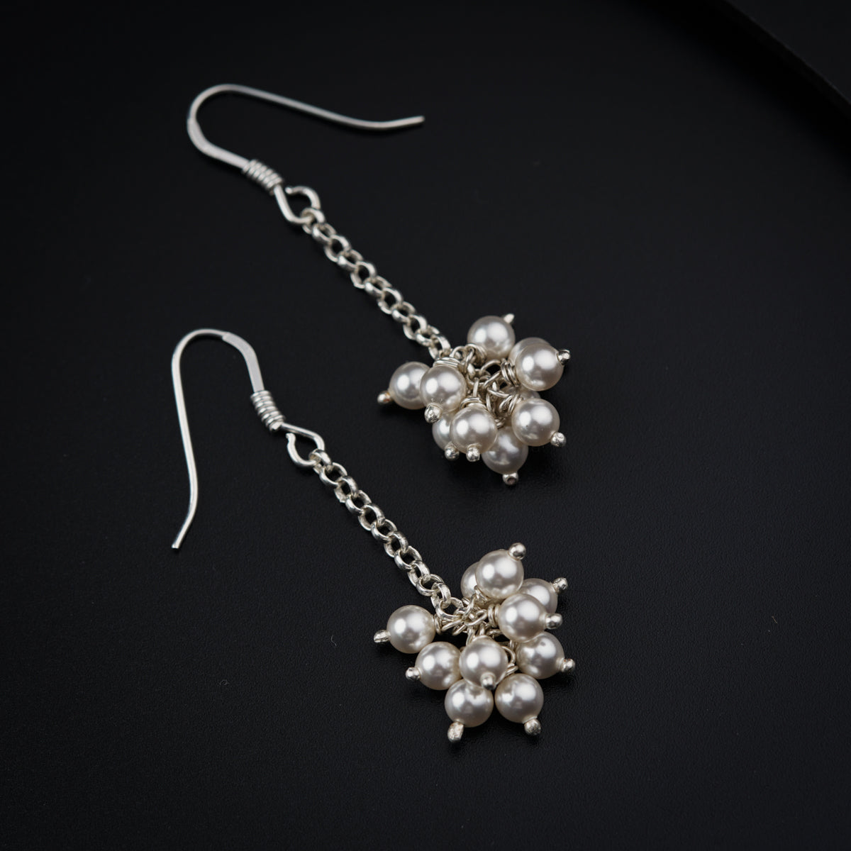 a pair of earrings with pearls hanging from them