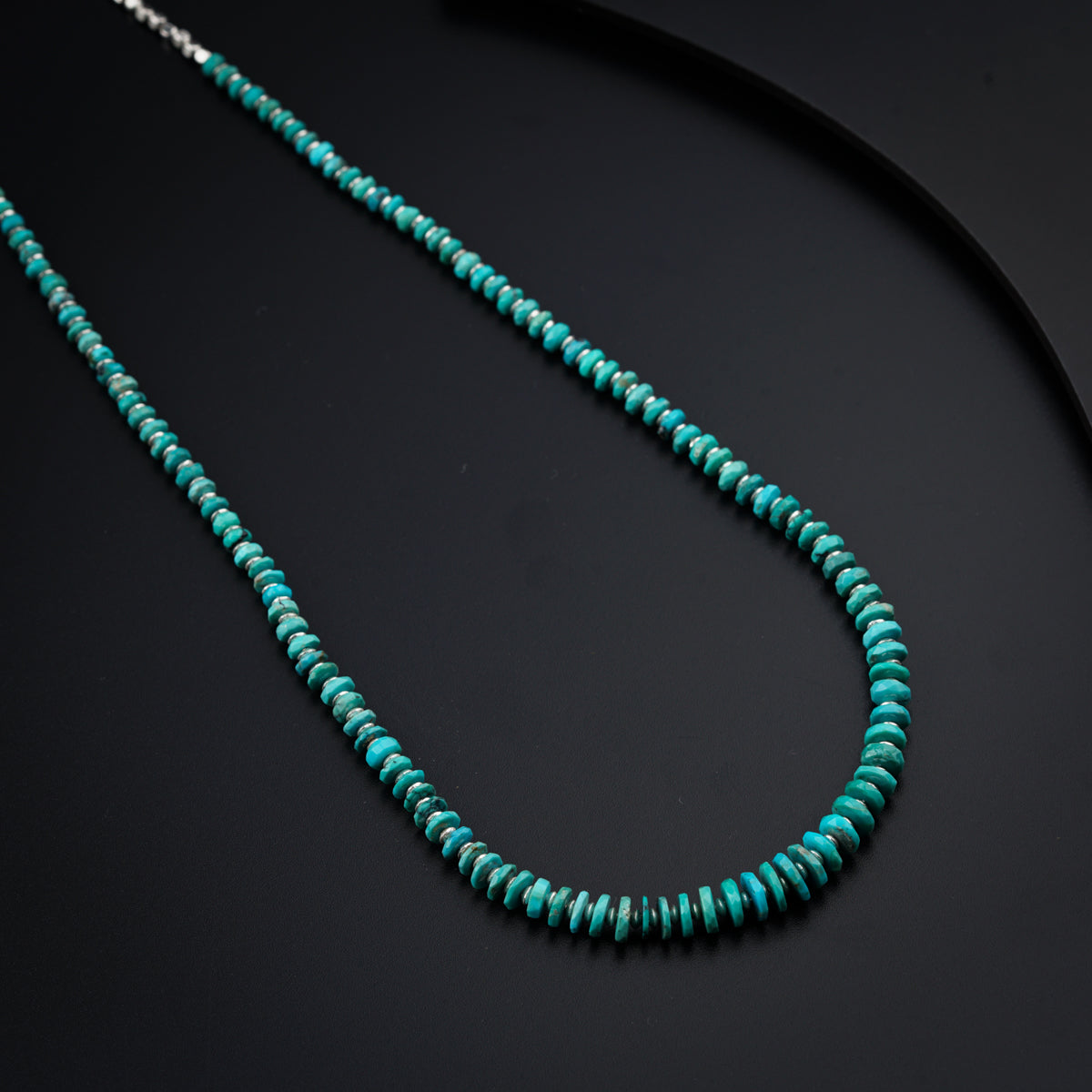 a turquoise beaded necklace on a black surface