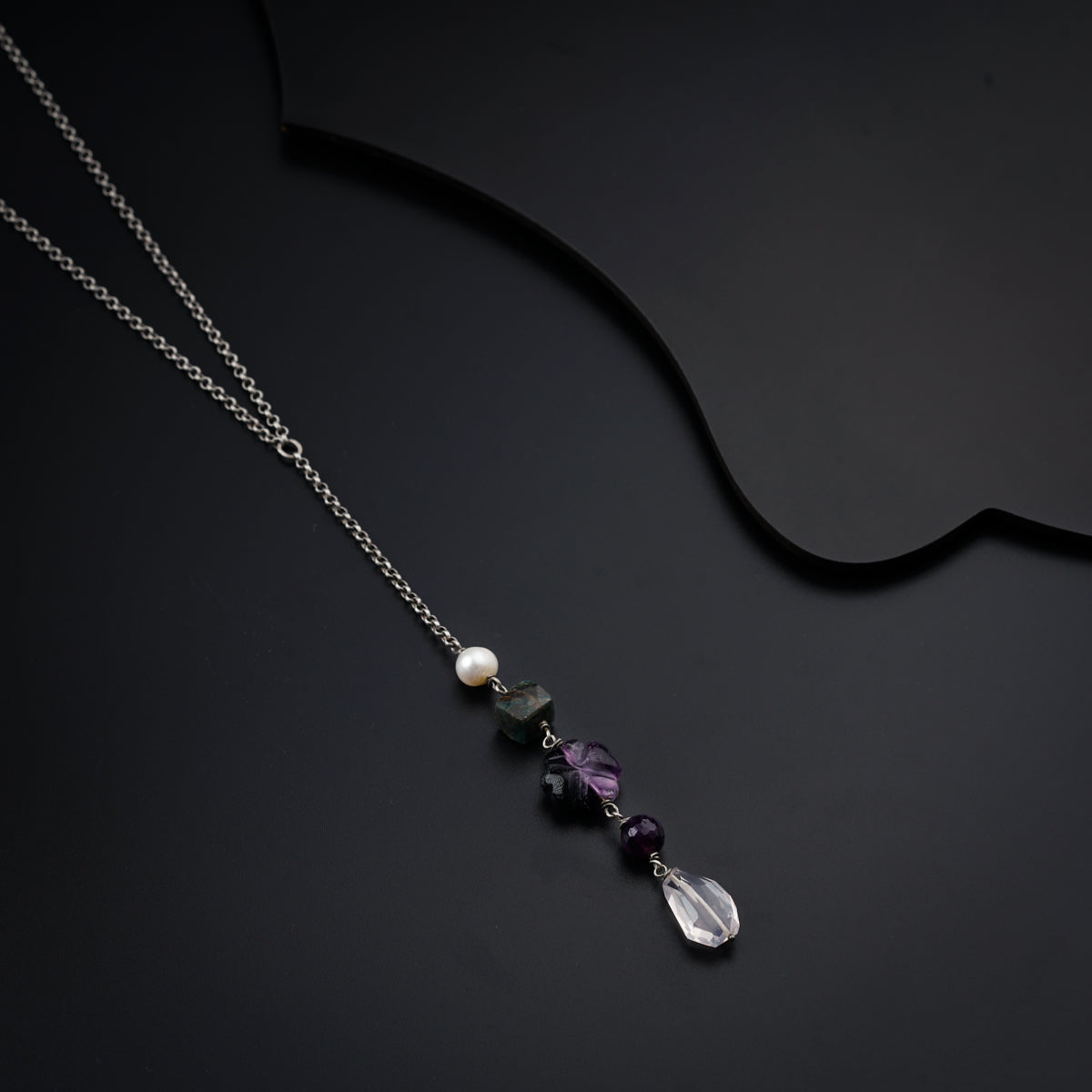 a silver necklace with a purple bead hanging from it