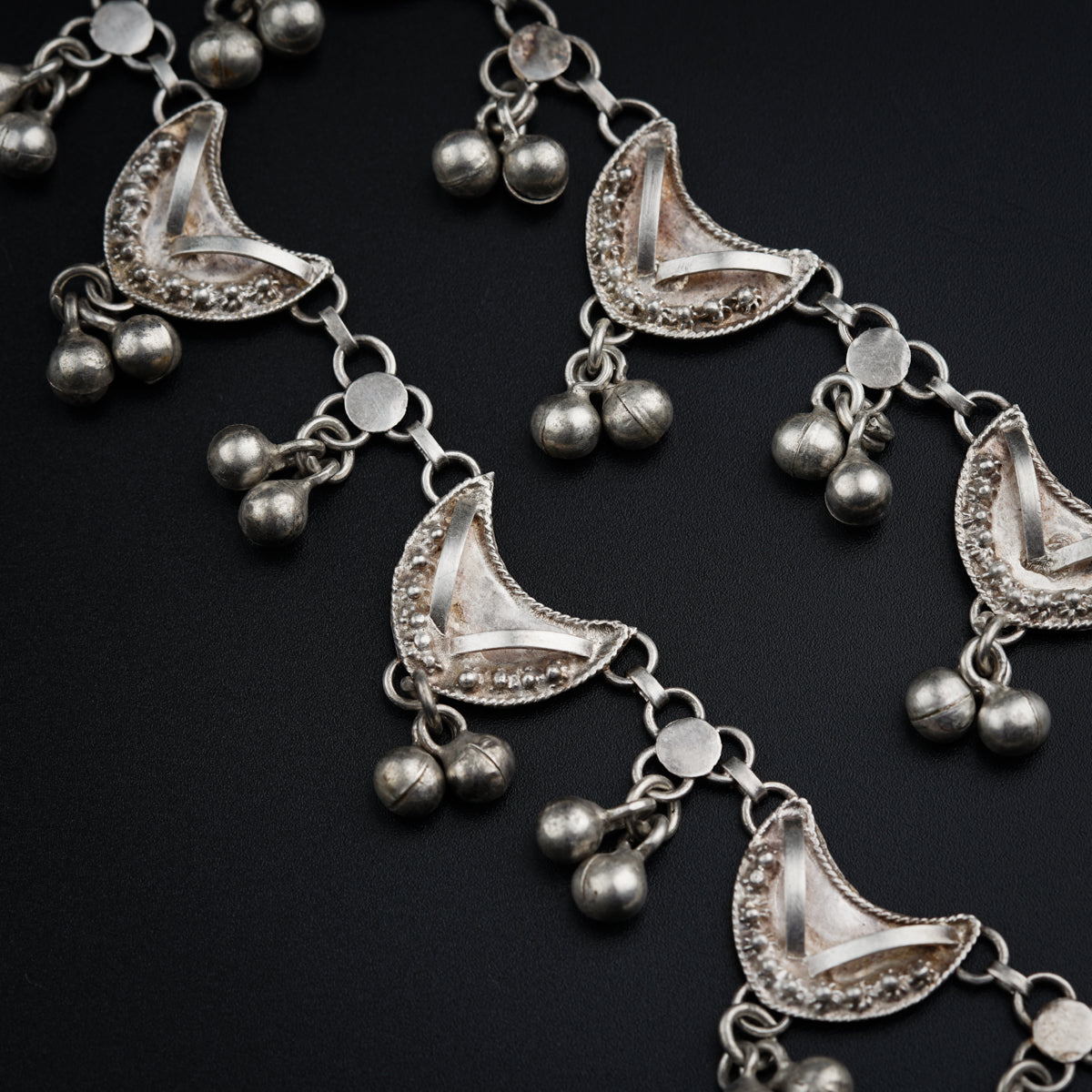 a close up of a silver necklace on a black surface