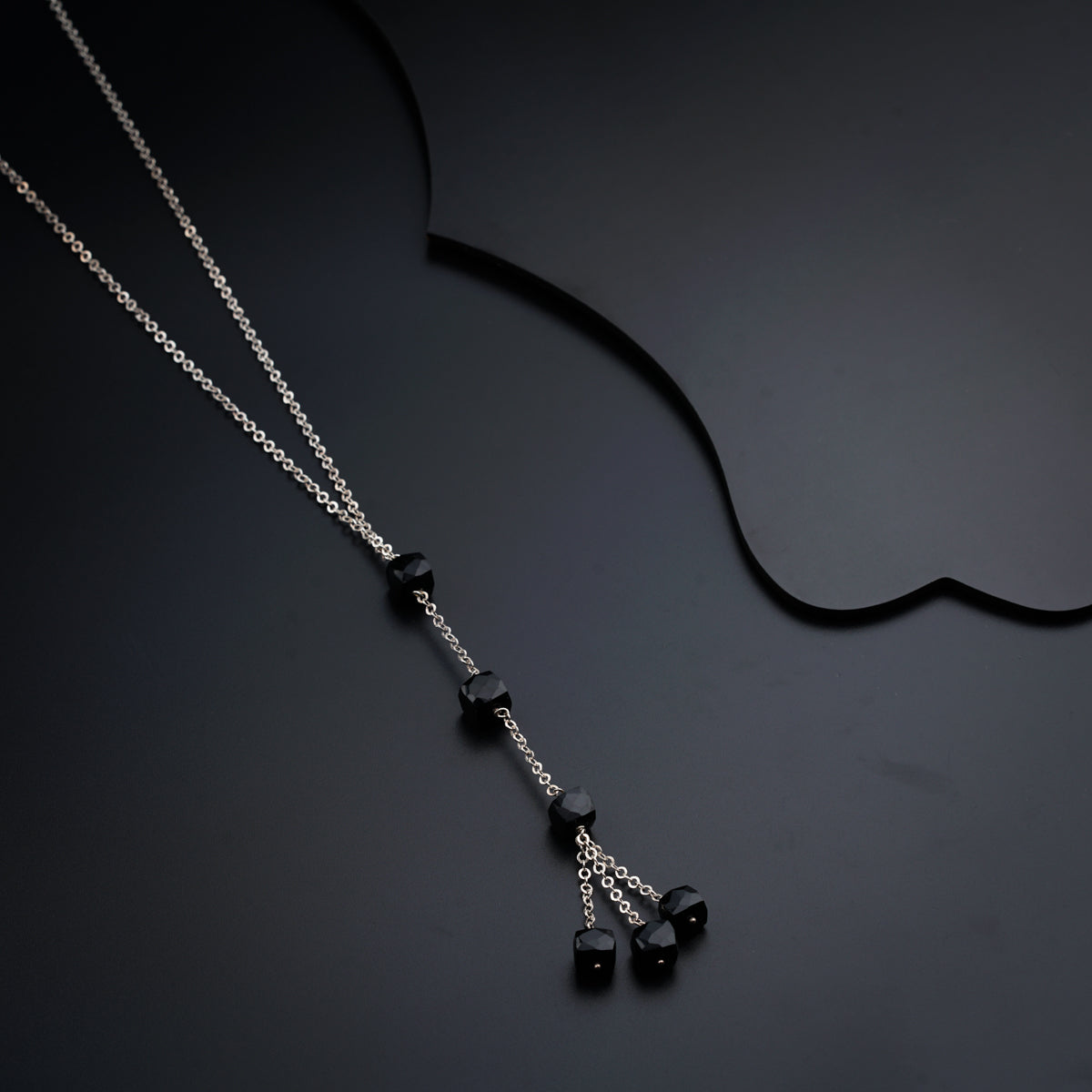 a black and silver necklace on a black surface