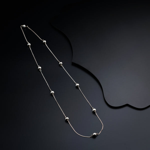 a silver necklace with beads on a black background