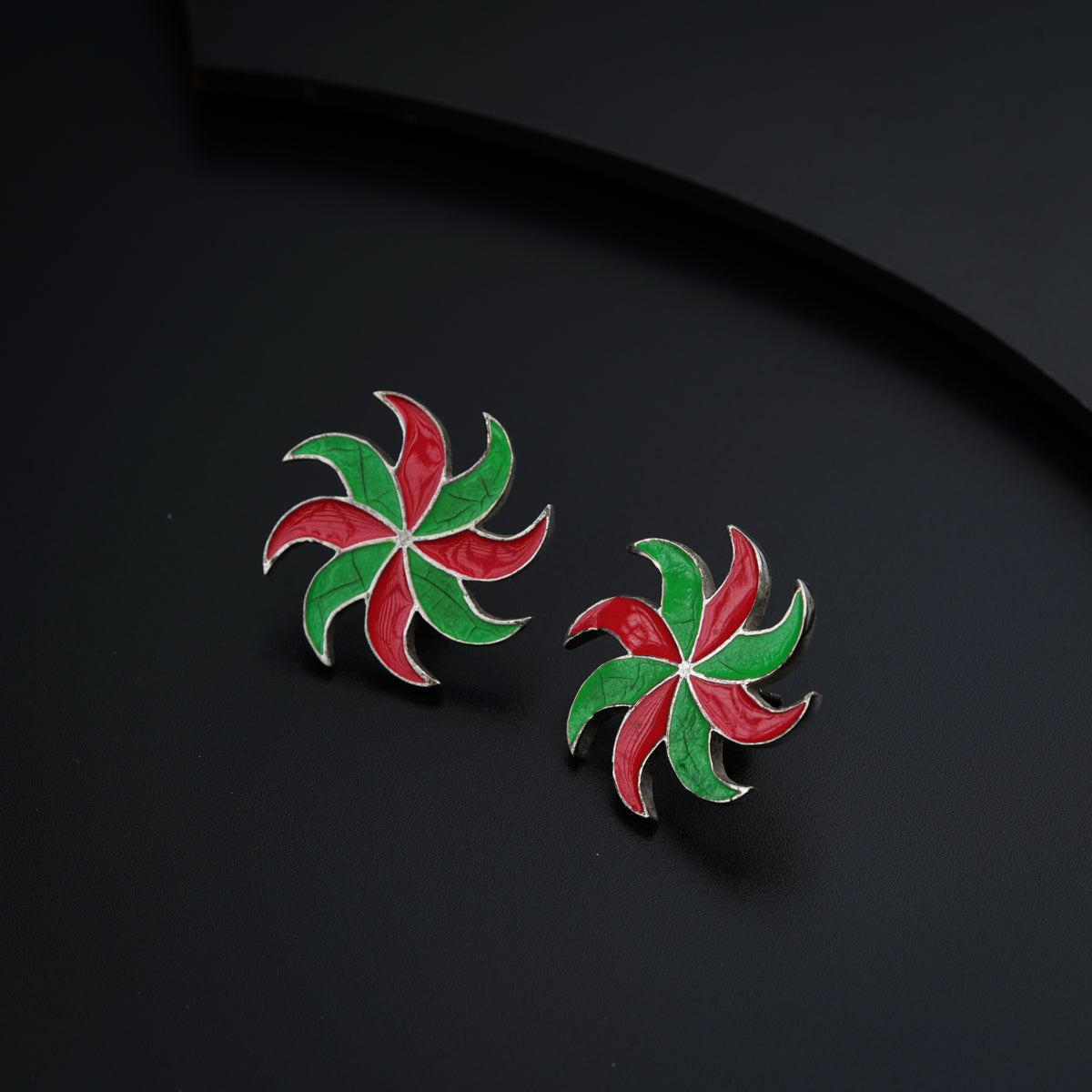 a pair of red, green and white earrings on a black surface