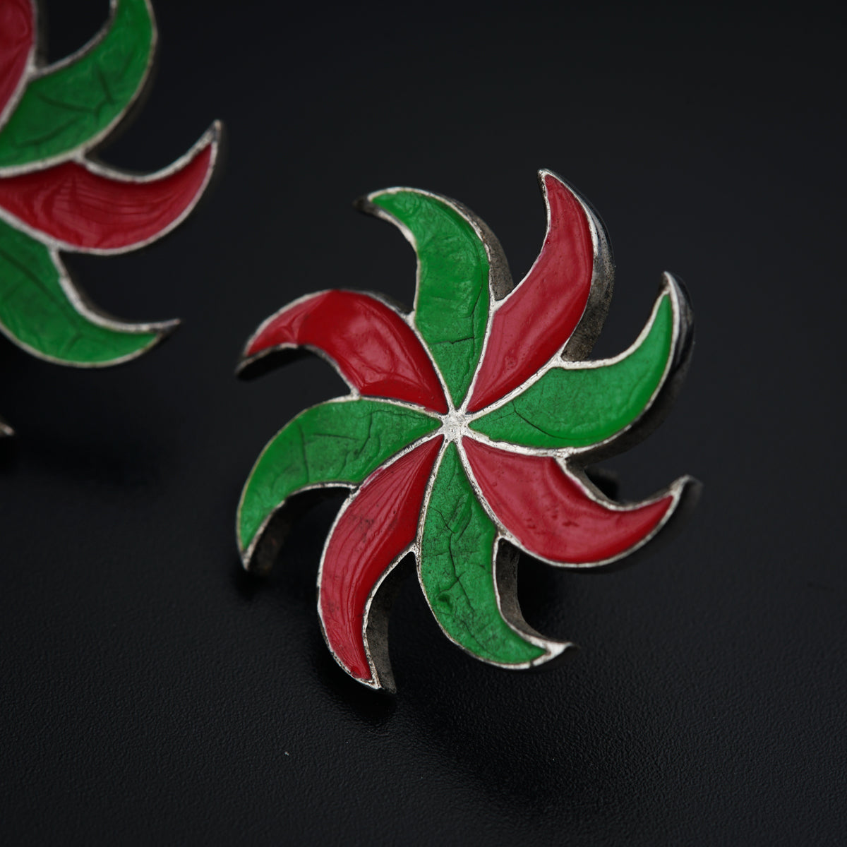 a pair of red, green and white earrings on a black surface