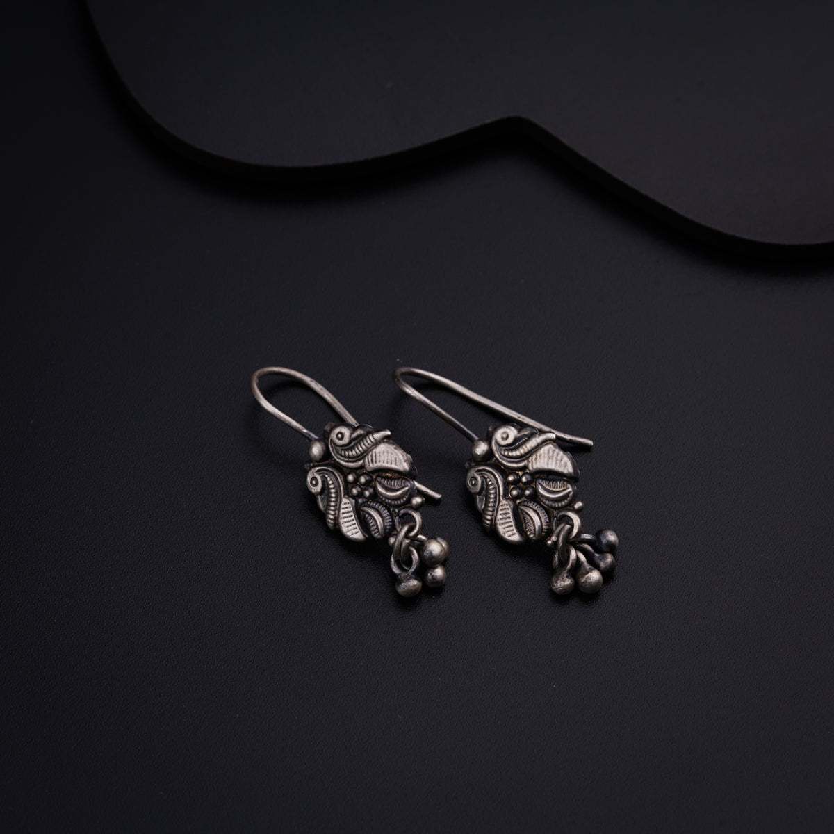a pair of silver earrings sitting on top of a black surface