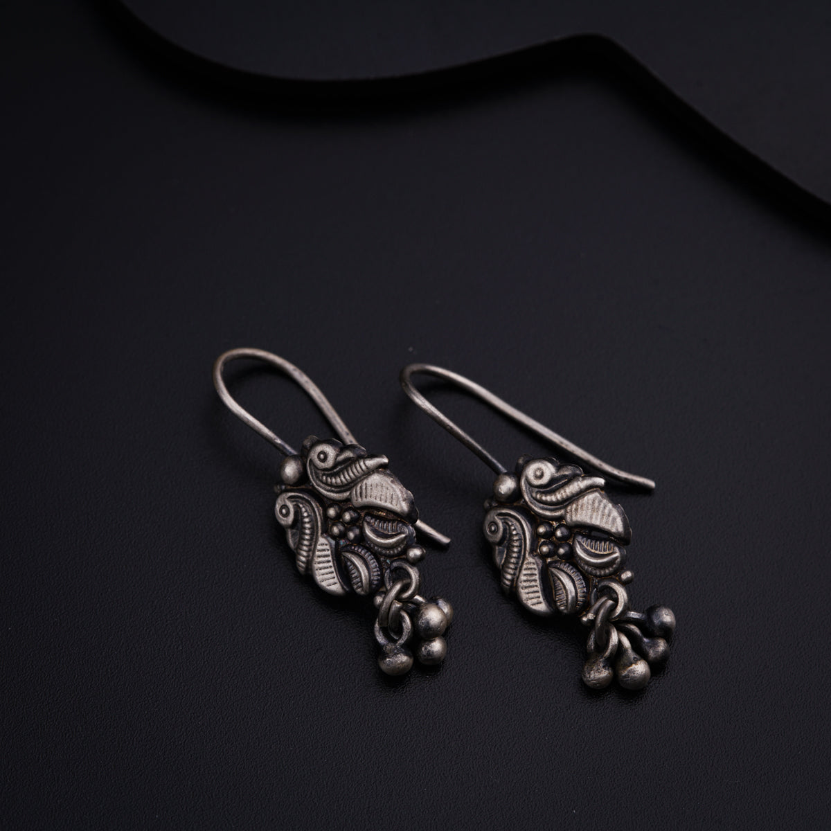 a pair of silver earrings on a black surface