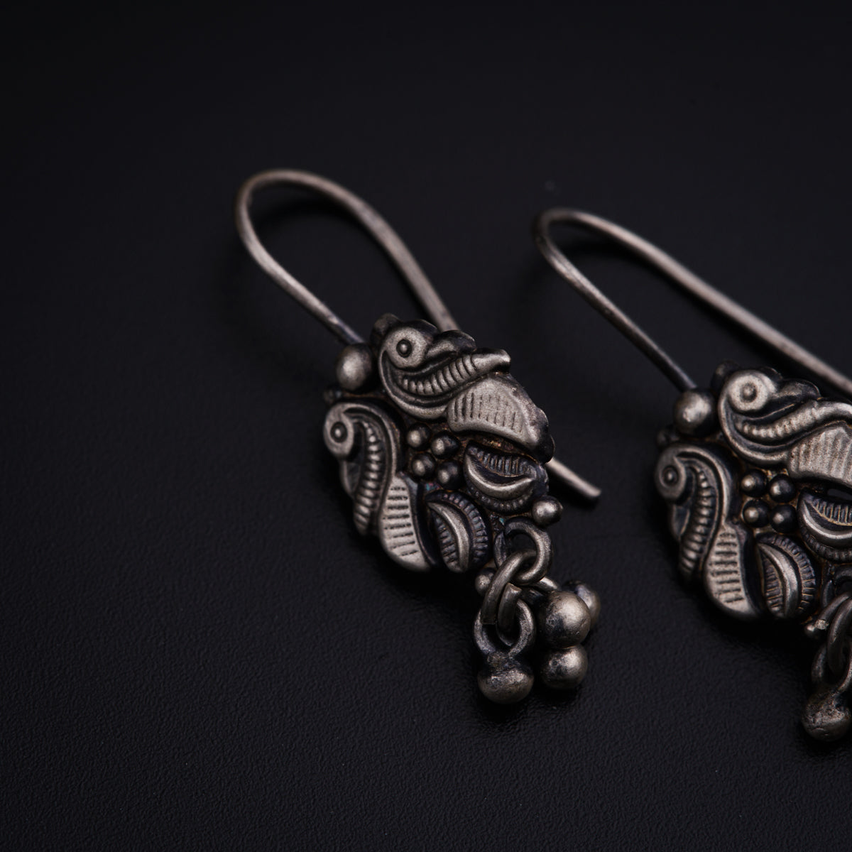 a pair of silver earrings on a black surface