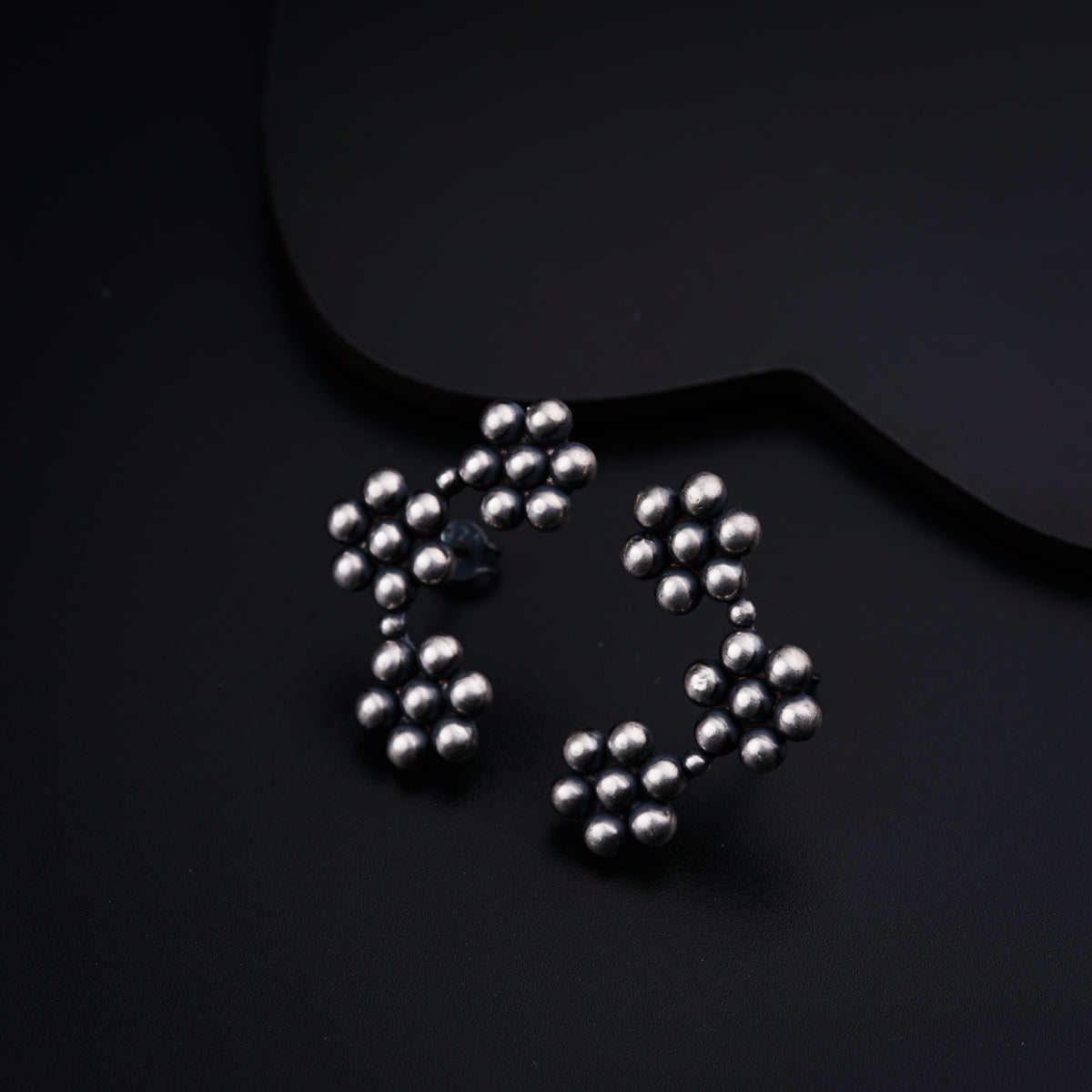 a pair of silver beads on a black surface