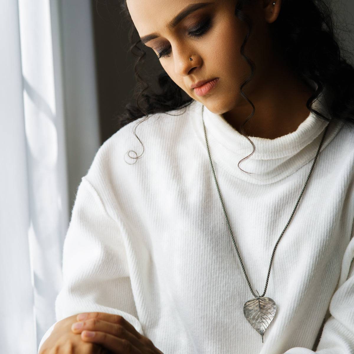 a woman wearing a white sweater and holding a cell phone