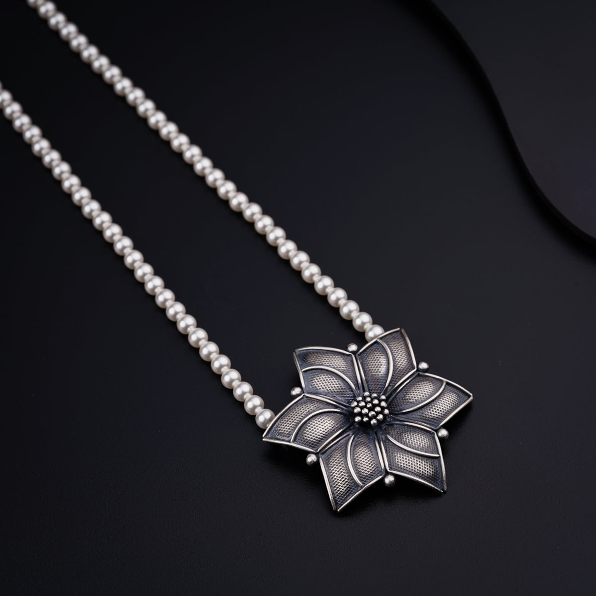 a silver necklace with a flower on it