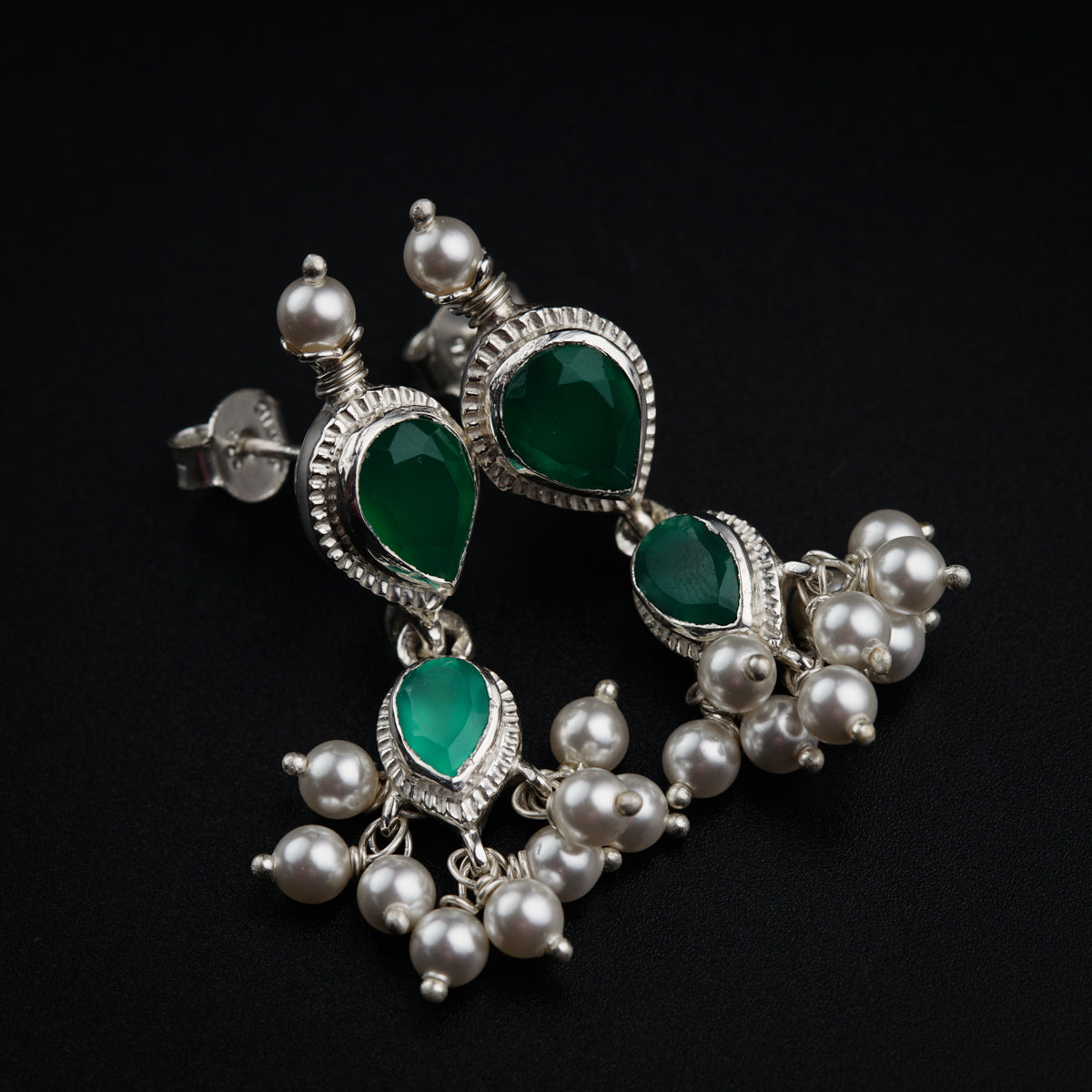 a pair of green and white earrings on a black background