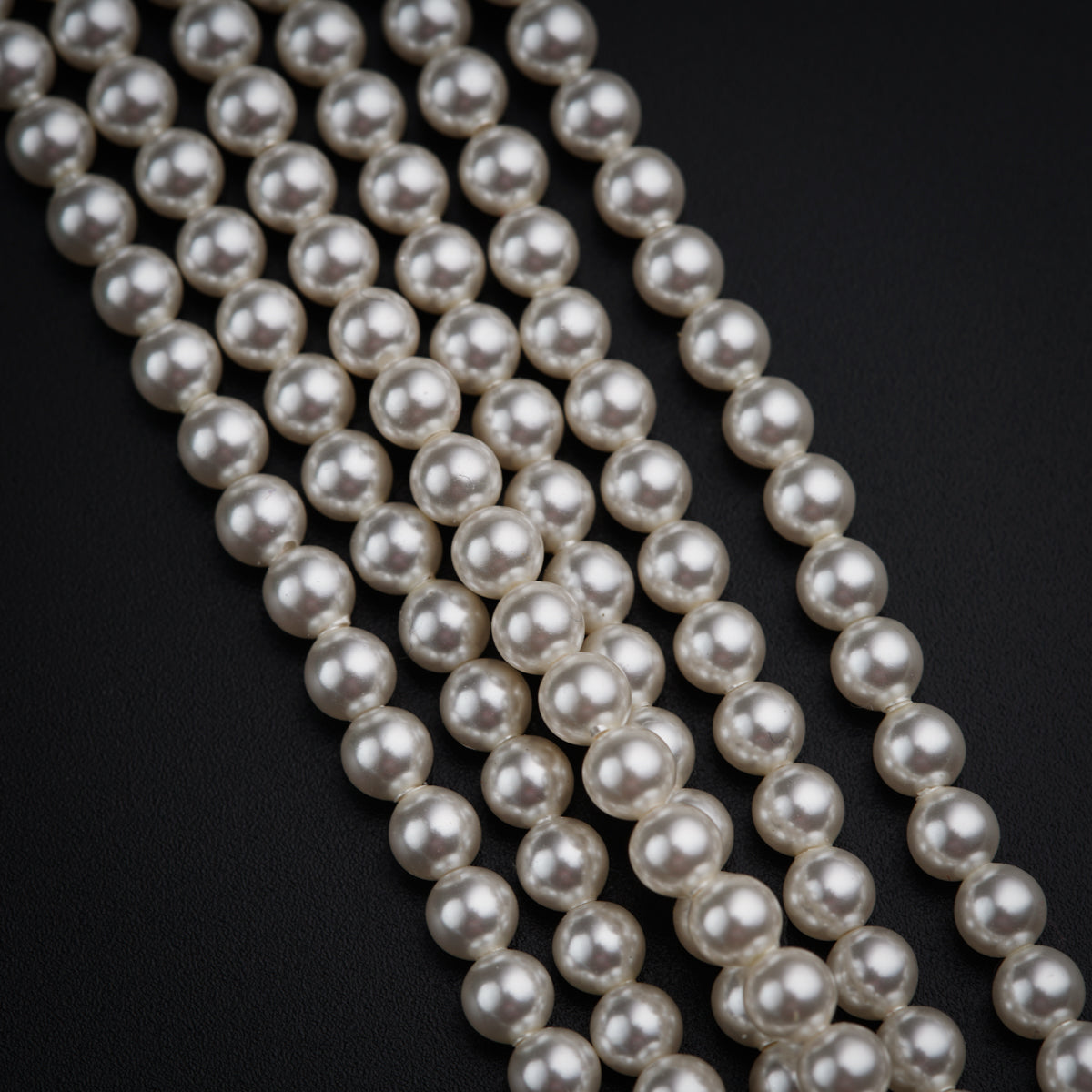 three strands of white pearls on a black background