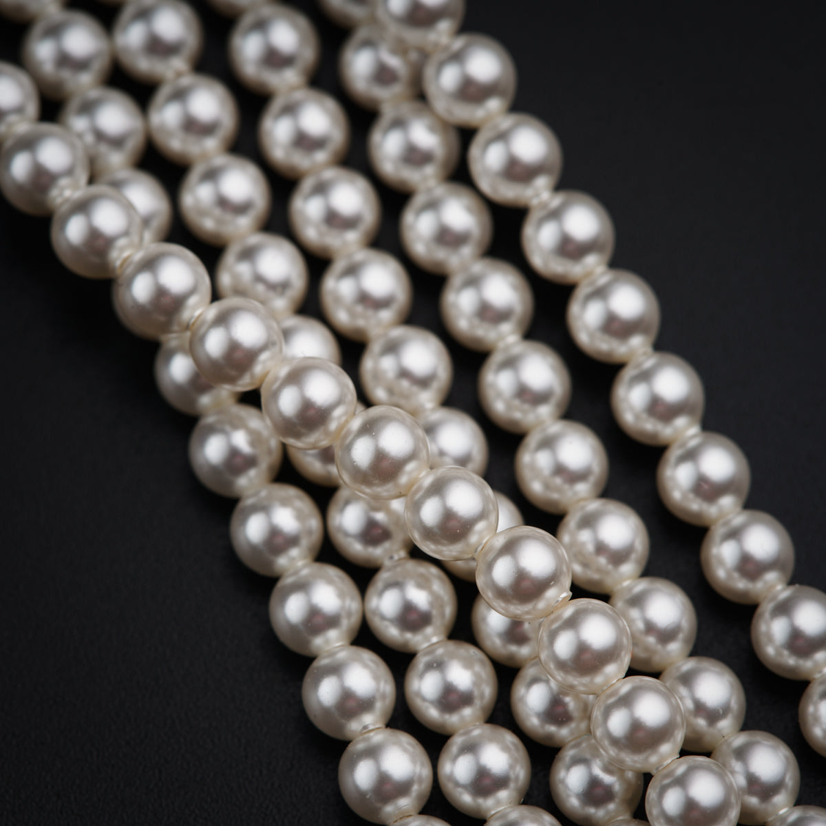 three strands of white pearls on a black background